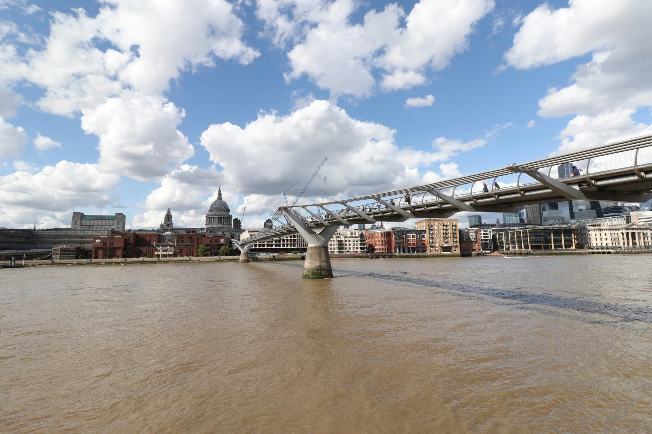 View of a large bridge over a river with an urban skyline