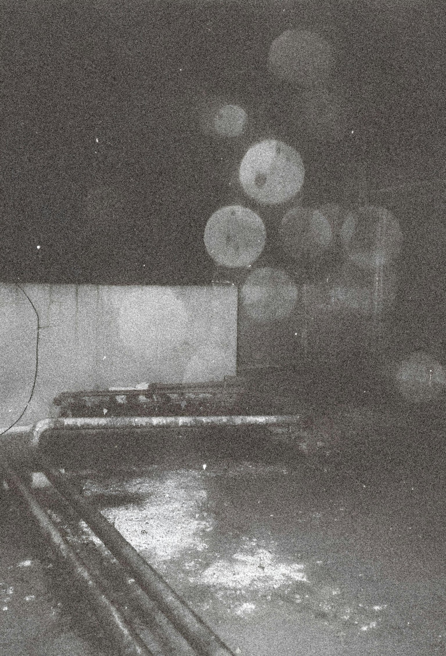 Hình ảnh khu vực tối với vũng nước và ống dẫn có ánh sáng tròn mờ