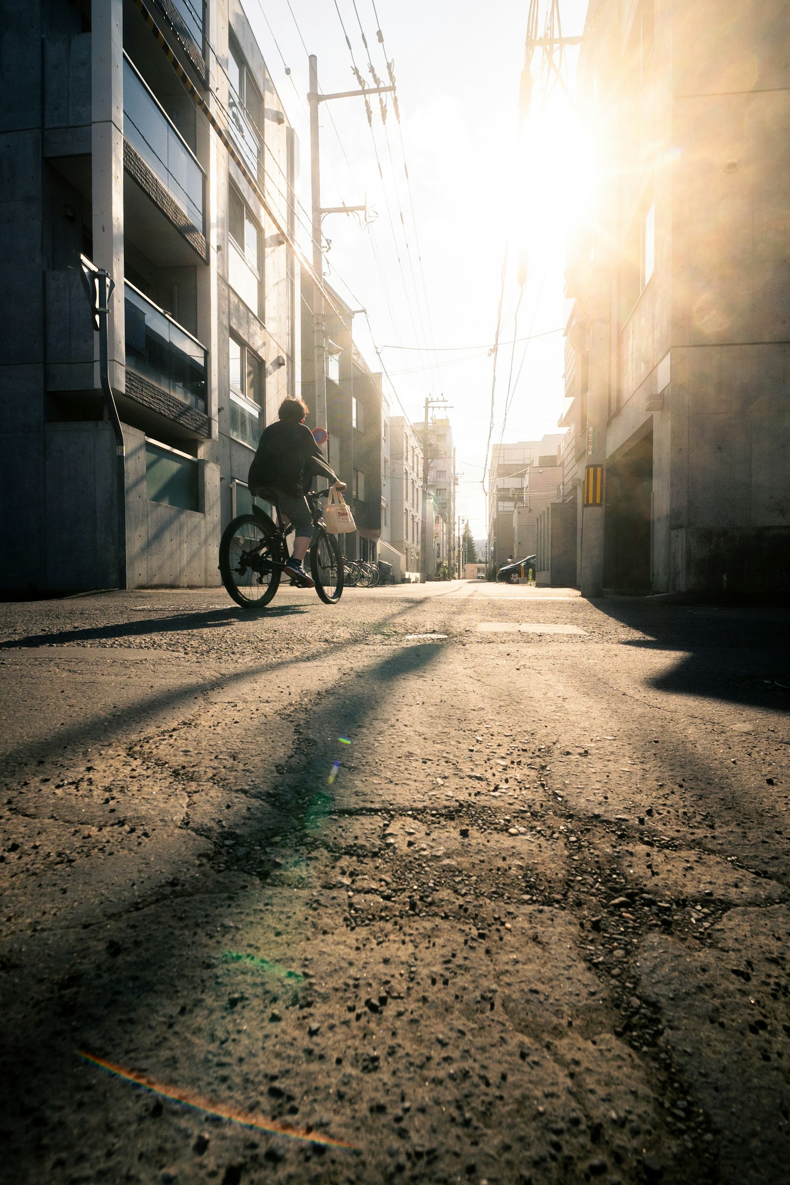 Une personne faisant du vélo dans une ruelle étroite avec le coucher de soleil en arrière-plan