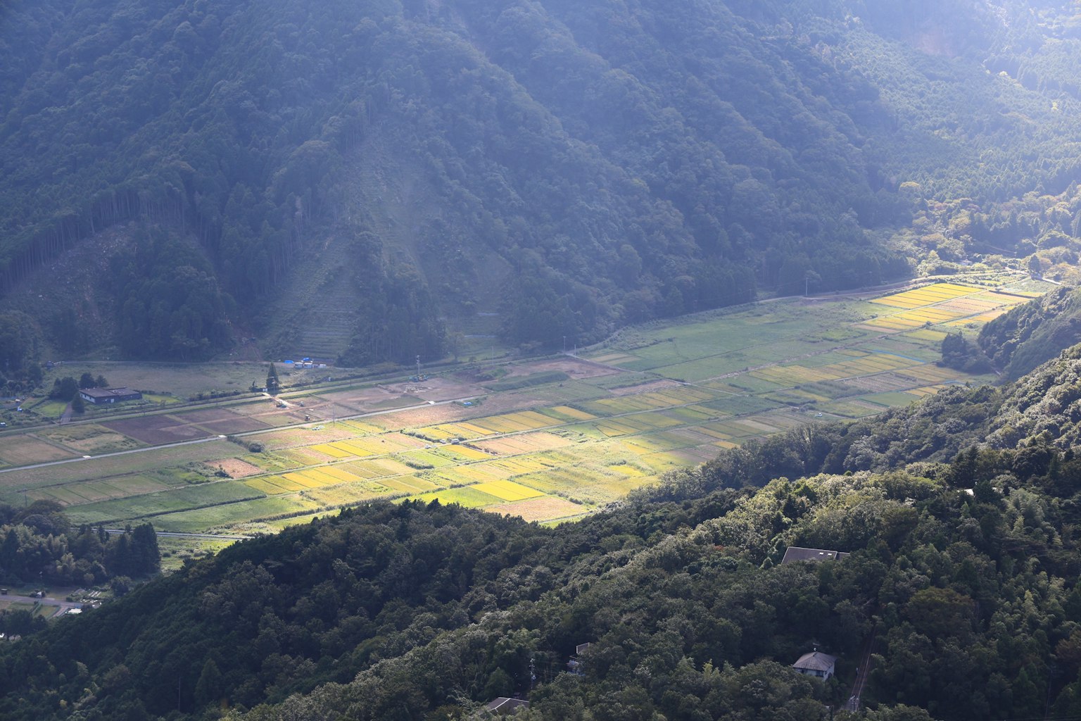 Vue aérienne de terres agricoles vertes et jaunes entourées de montagnes