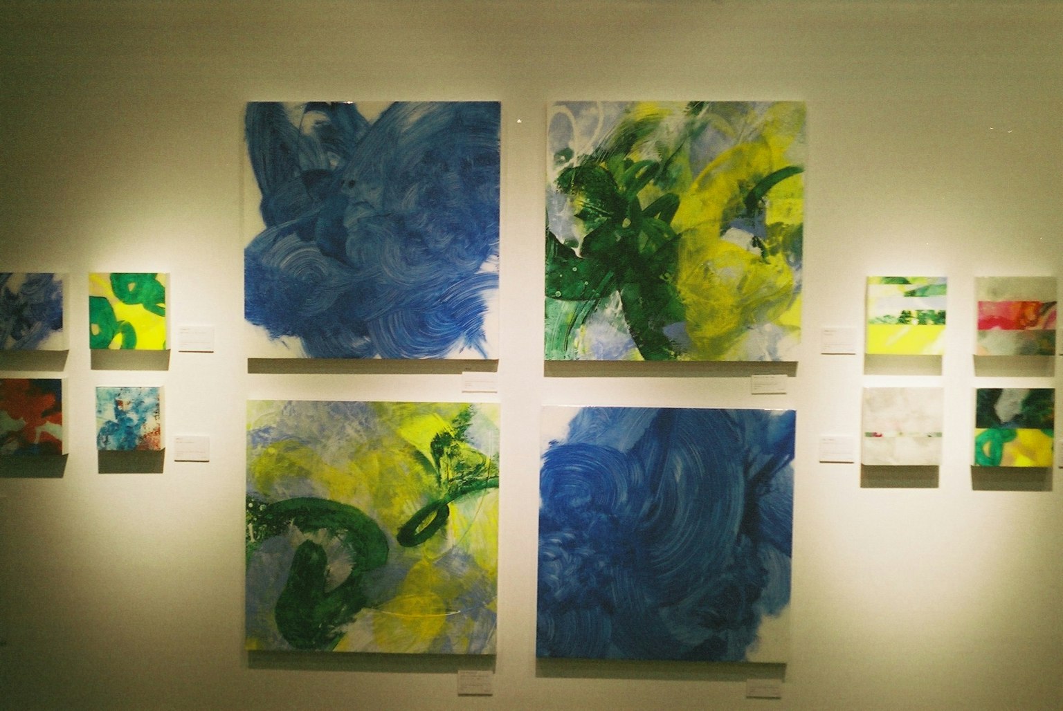 Gallery wall featuring vibrant abstract paintings in blue and green