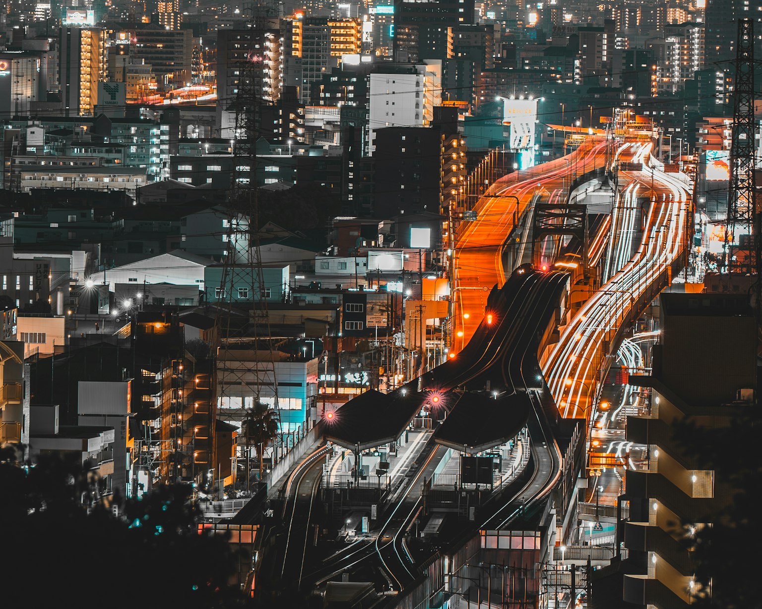 Pemandangan kota yang hidup di malam hari dengan rel kereta yang diterangi dan bangunan