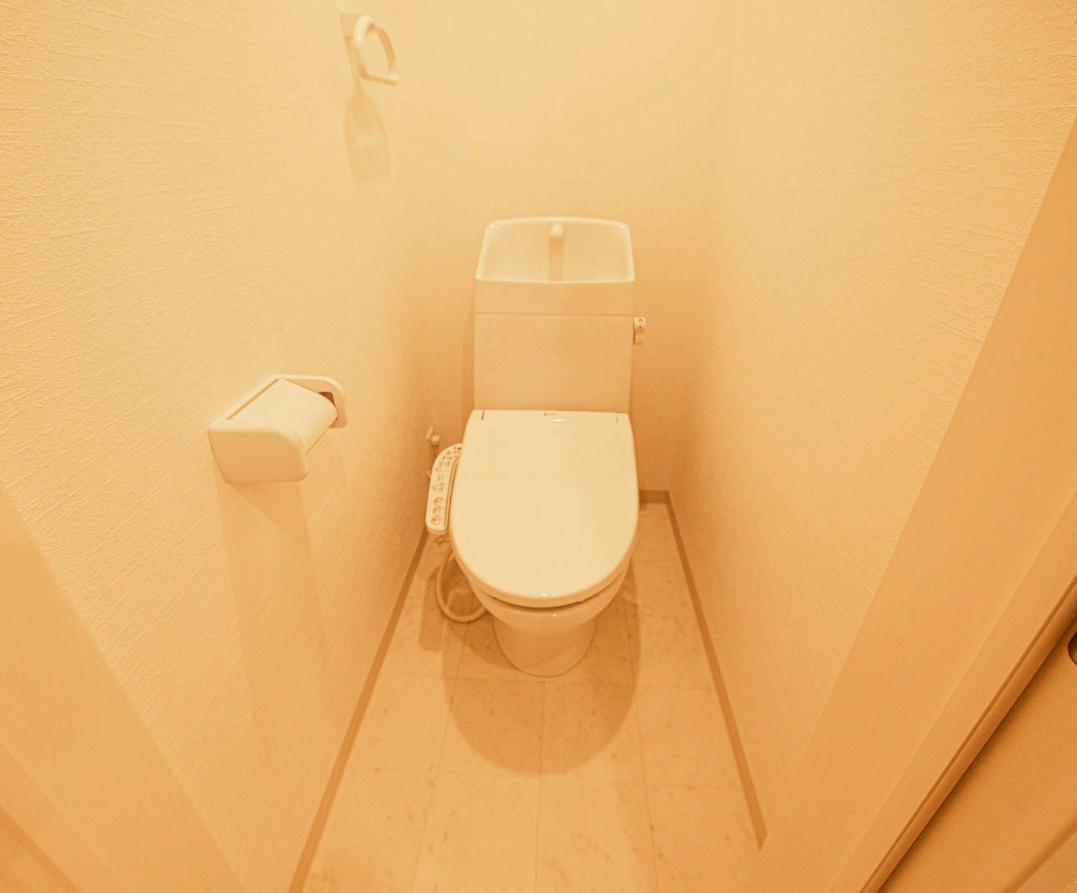 Interior de baño estrecho con inodoro blanco en un esquema de colores claros