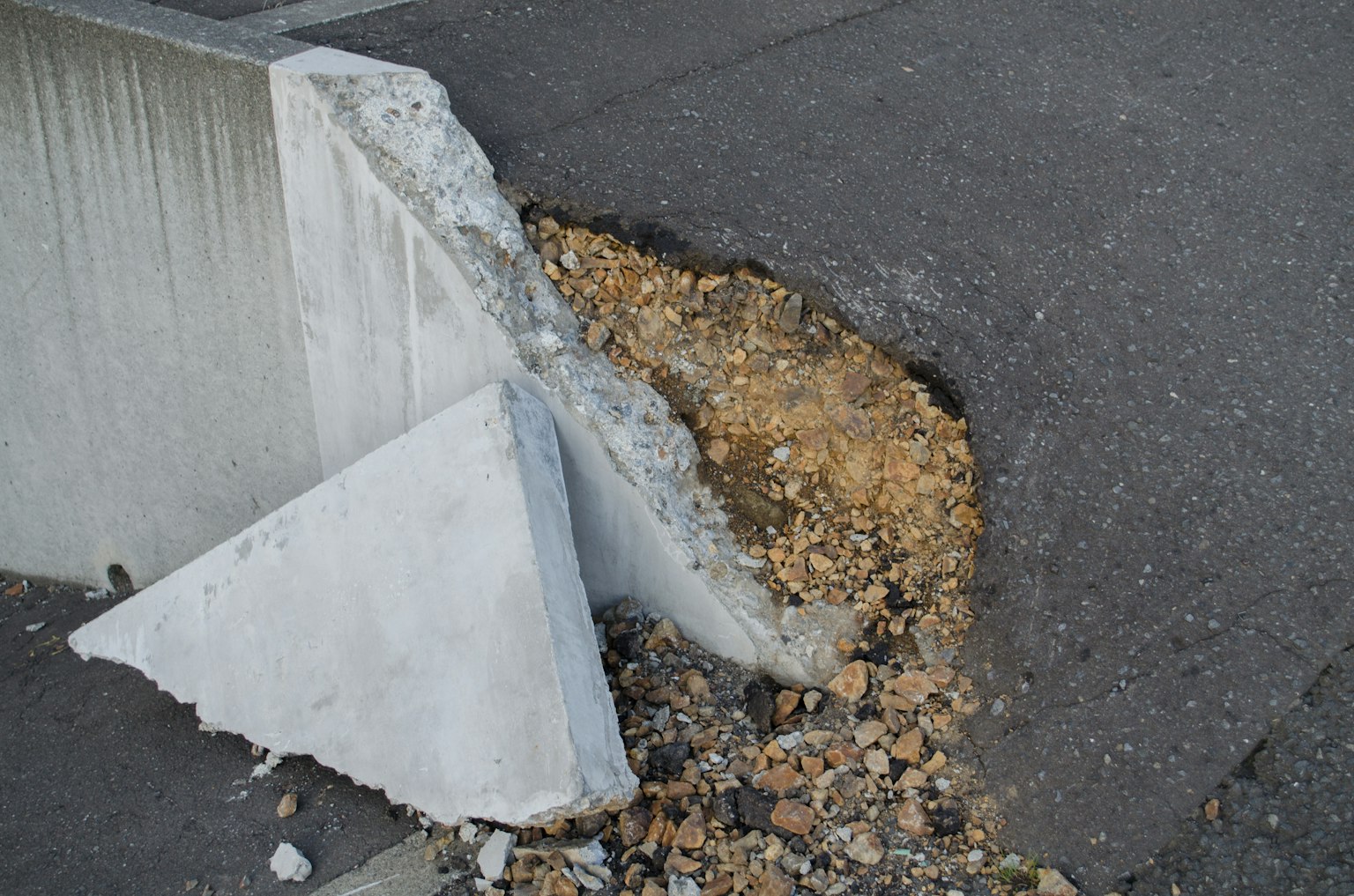 Barrière en béton endommagée avec des pierres accumulées