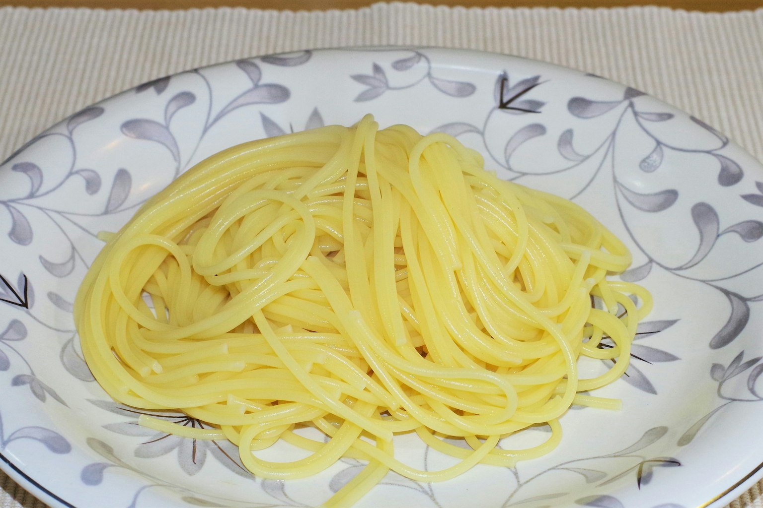 A serving of spaghetti on a decorative white plate