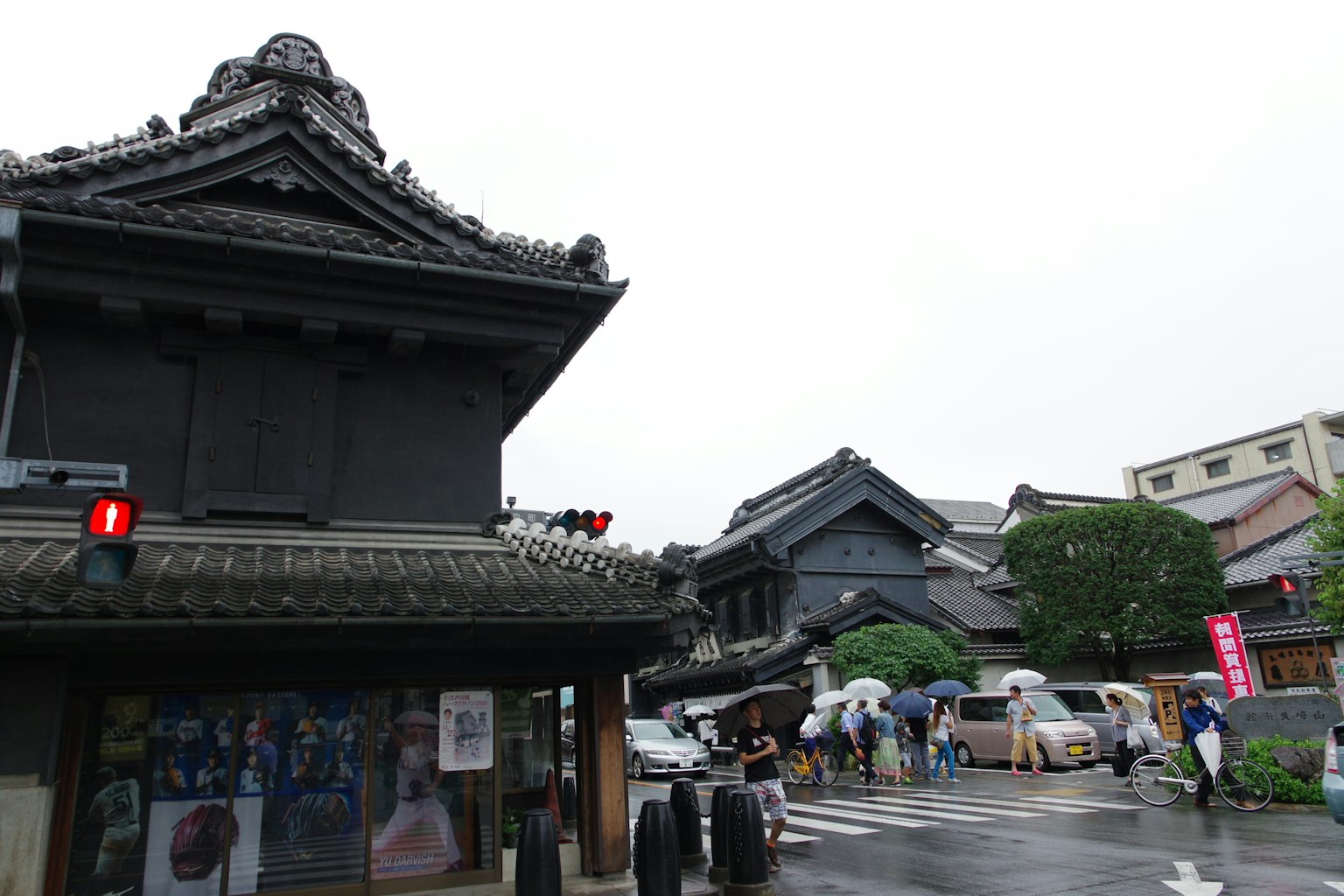 Persimpangan dengan arsitektur Jepang tradisional dan bangunan komersial modern di bawah hujan
