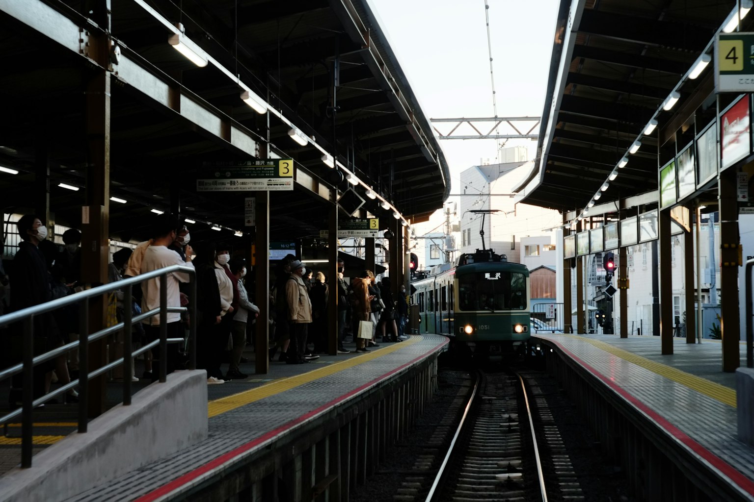 Kerumunan orang di platform stasiun kereta dengan kereta yang mendekat