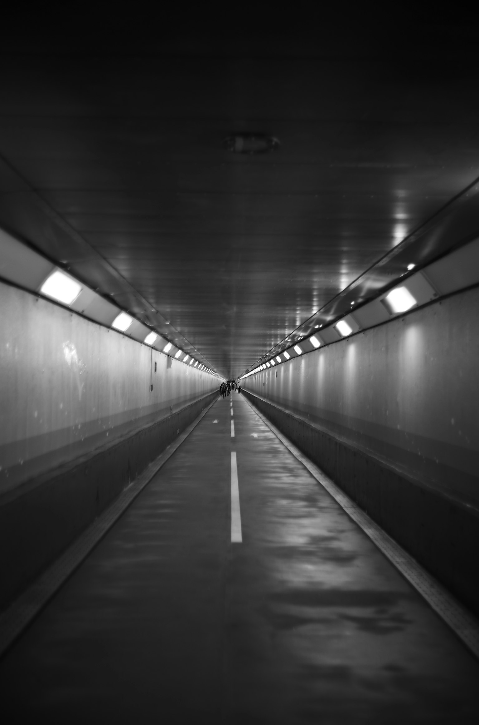 Dark tunnel with a straight path and overhead lights