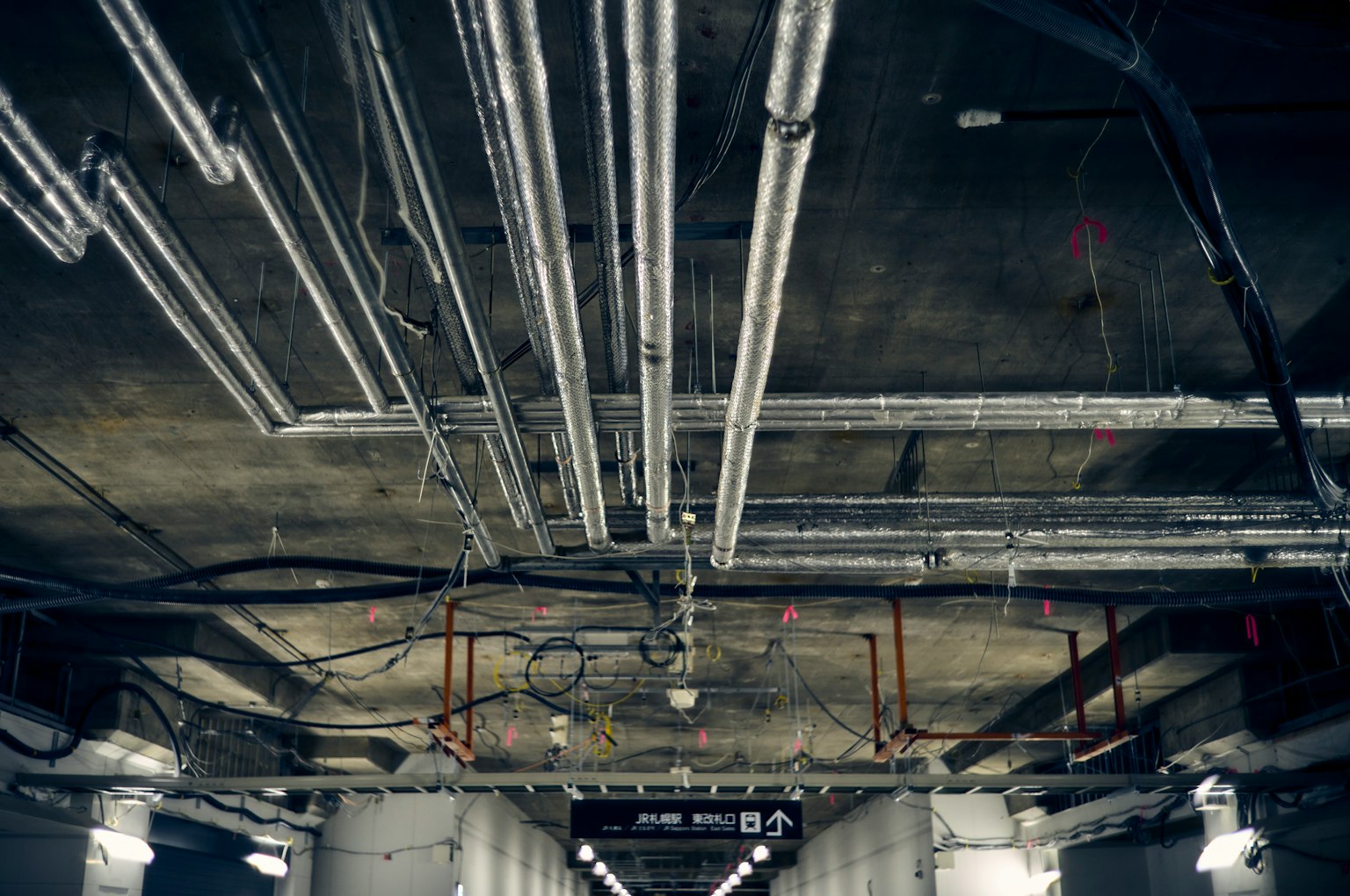 Close-up of metallic pipes and electrical wires on a ceiling