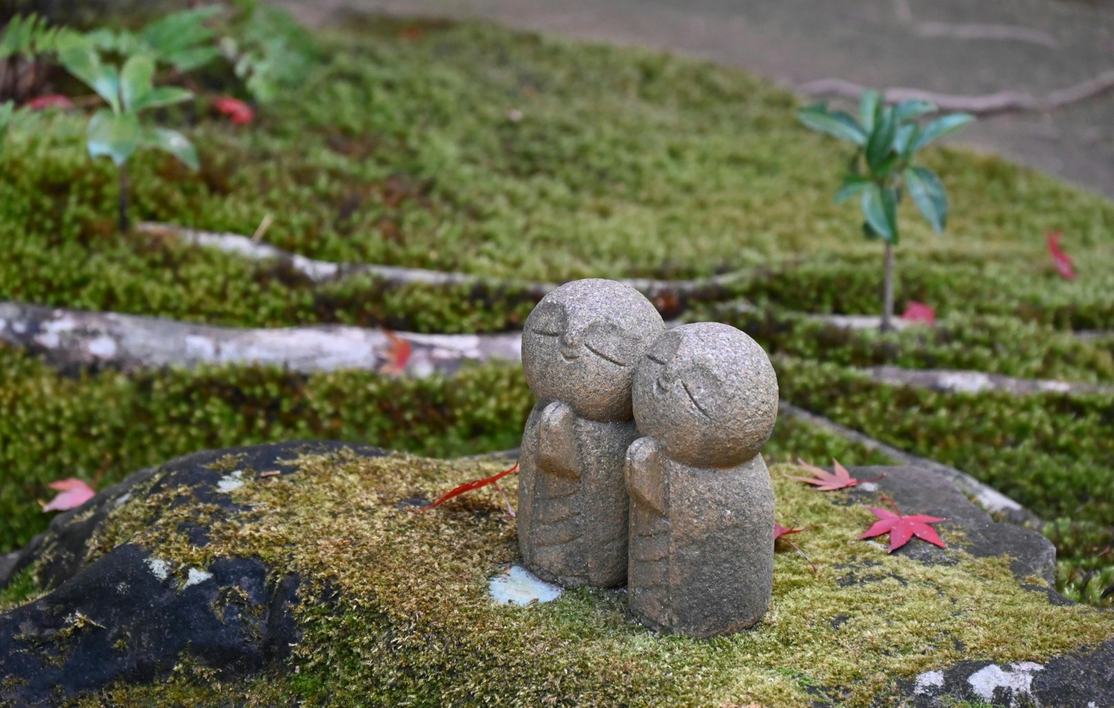 mossy garden stone statue with small tree ornament