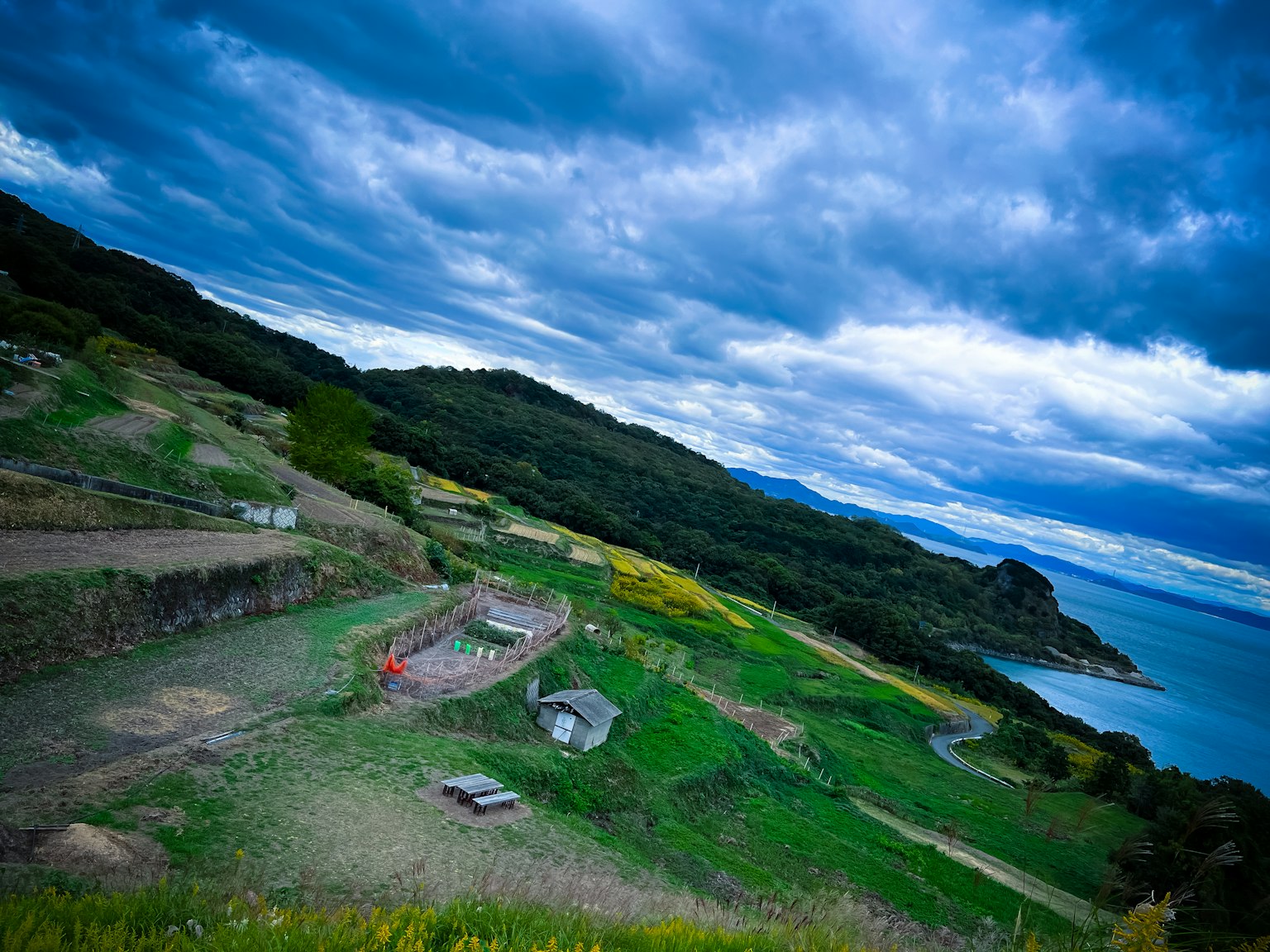 Paysage pittoresque avec des collines vertes et une petite maison sous un ciel bleu