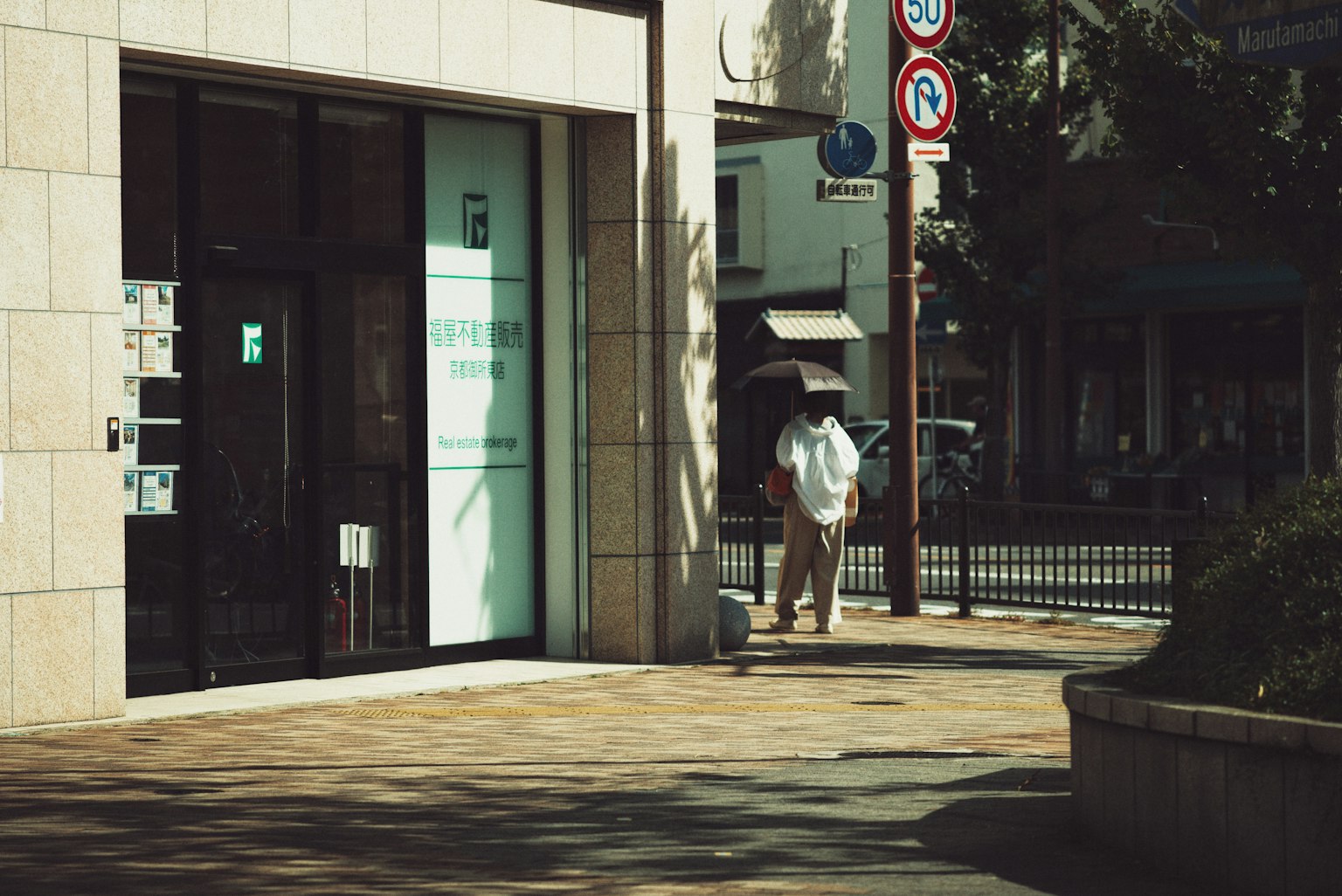A man in a white shirt walking on a street corner