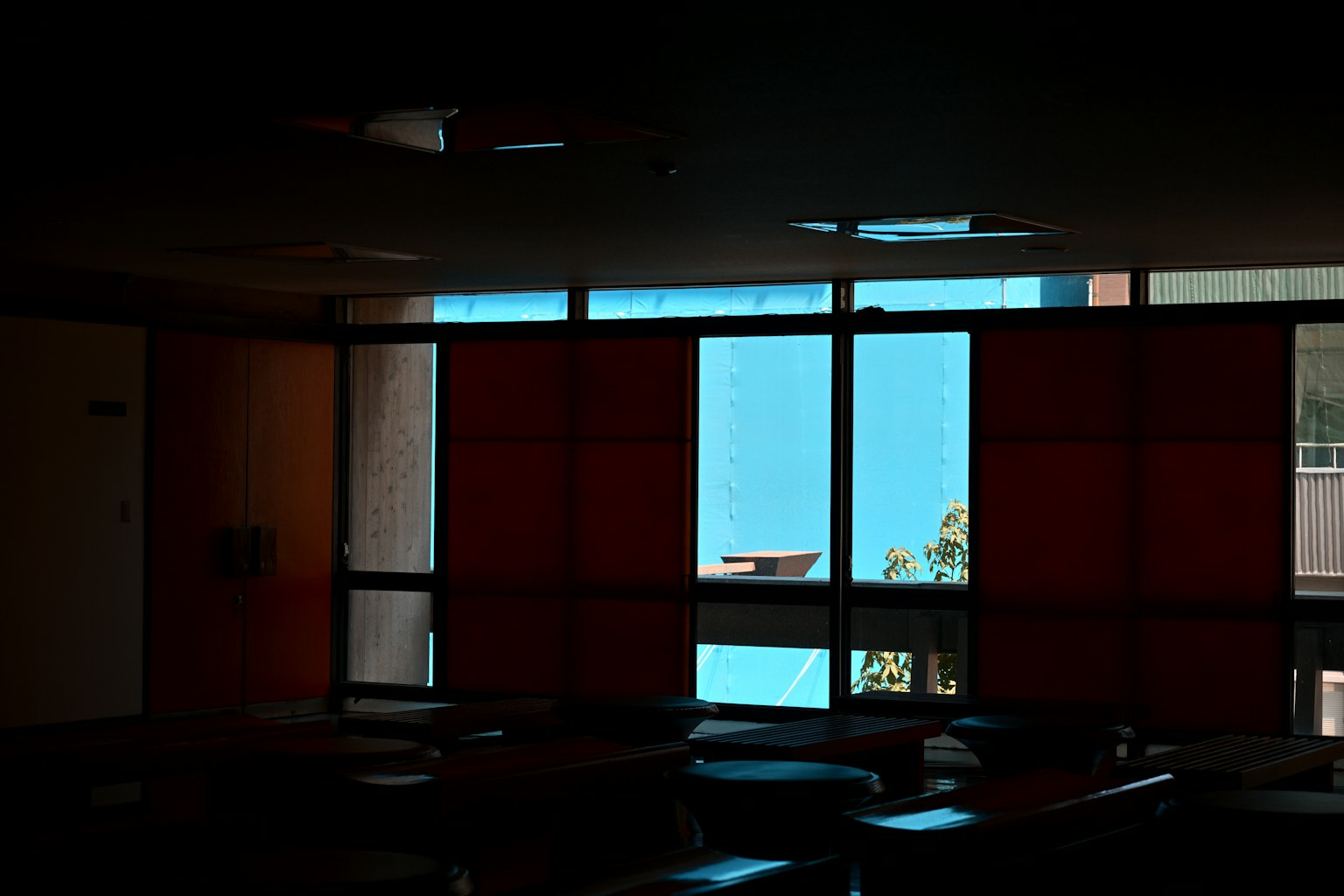 Interno poco illuminato con vista su un muro blu e tende rosse
