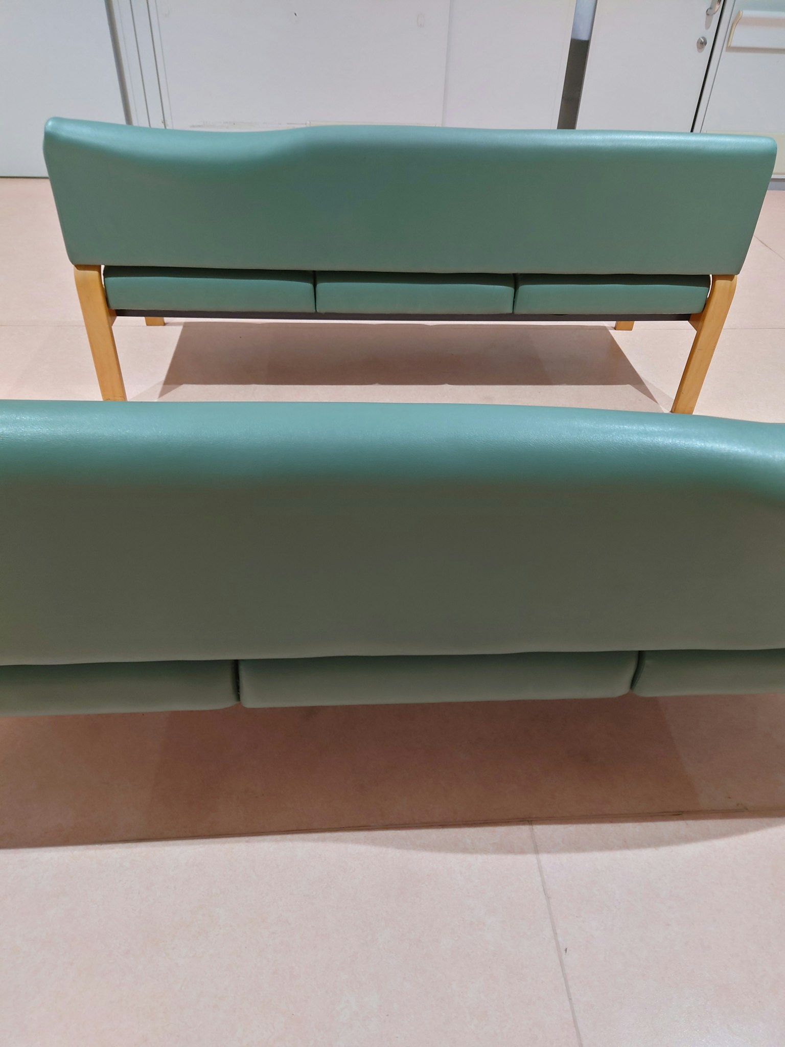 Due divani verdi con schienali visibili disposti in uno spazio moderno