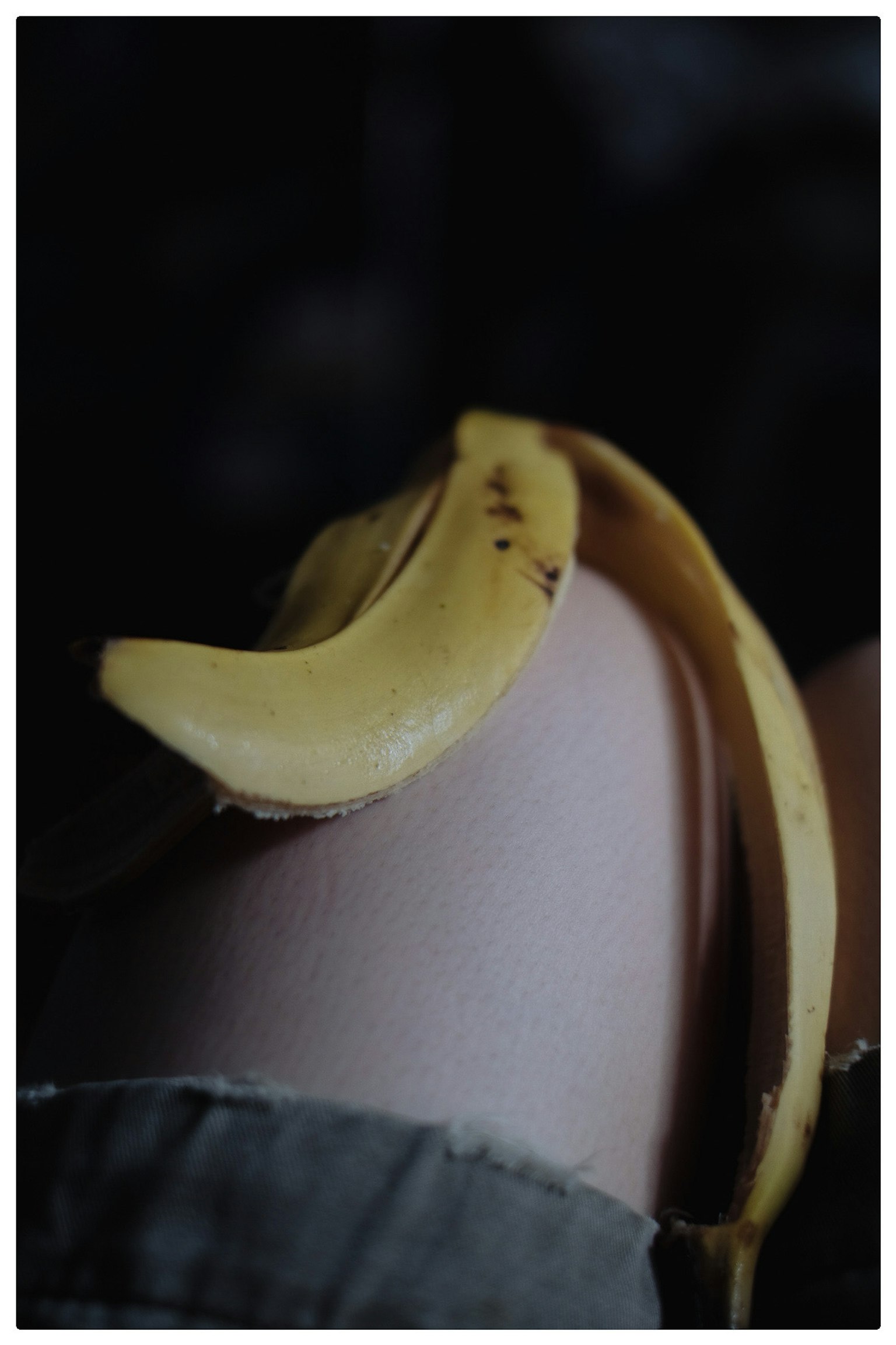 Una banana appoggiata sul ginocchio di una persona in bassa luce