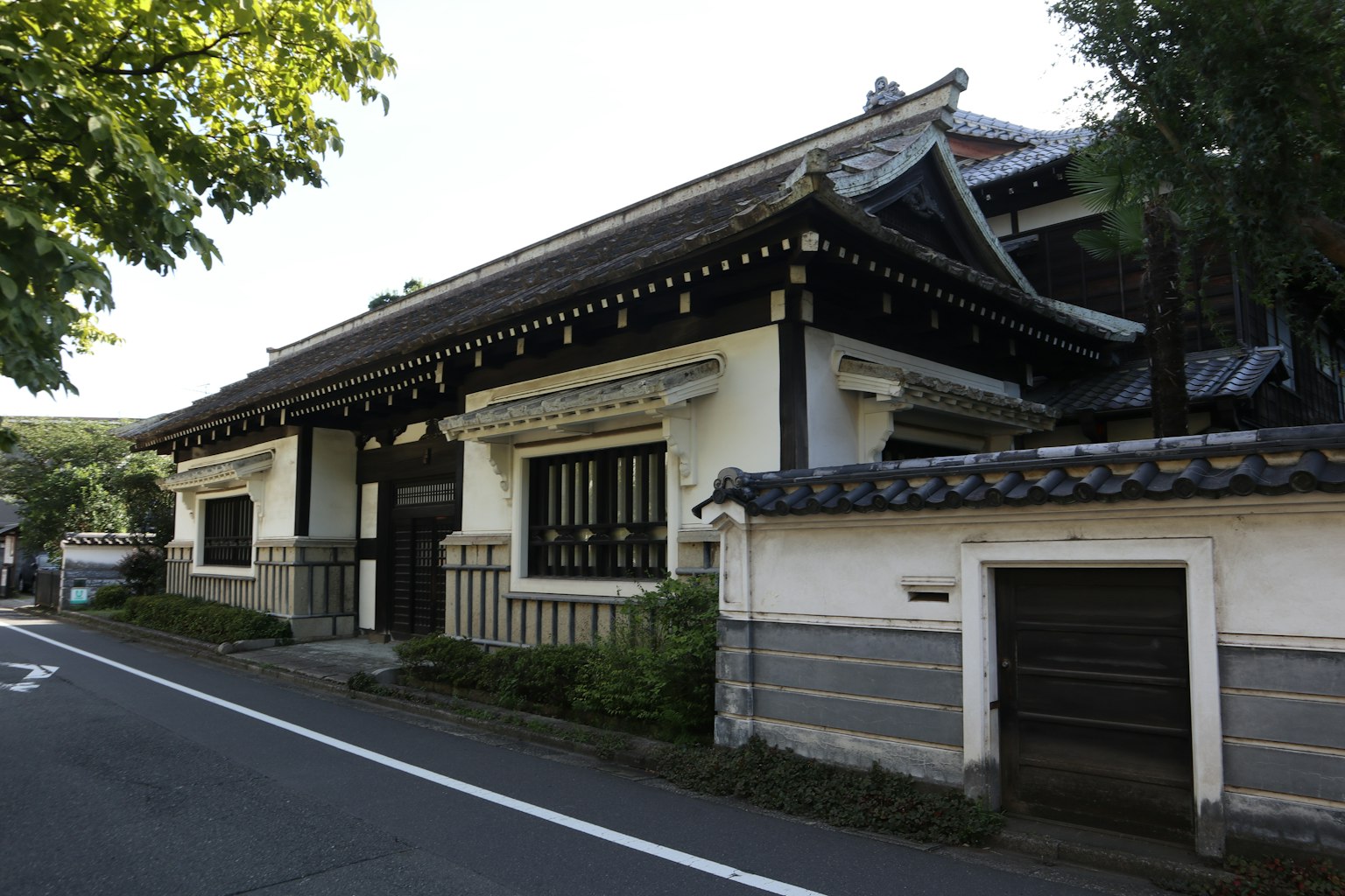 傳統日本建築，白牆黑頂，周圍環繞著綠色樹木