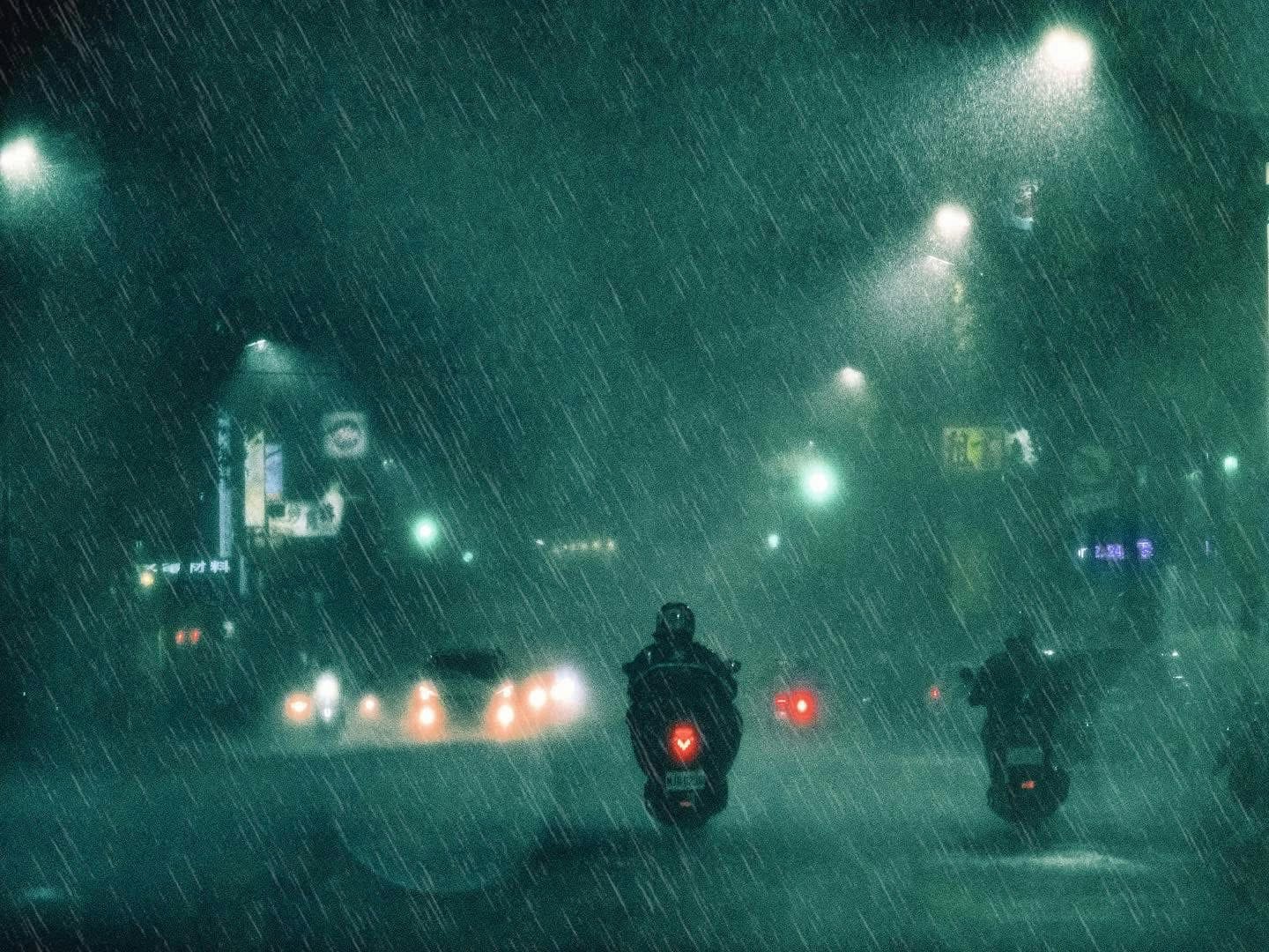 雨の夜の道路を走るバイクのテールライト