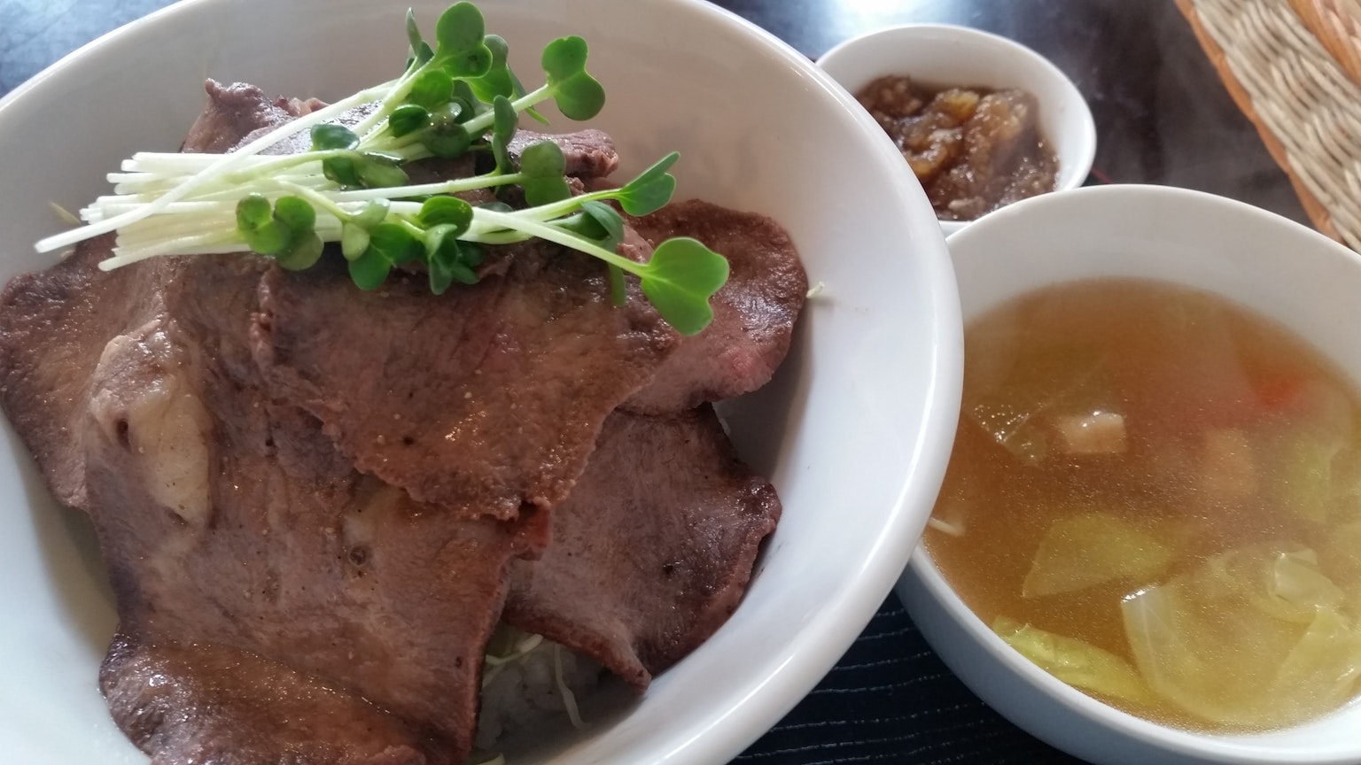 Mangkuk daging sapi iris dihiasi dengan herba dan daun bawang disajikan dengan sup