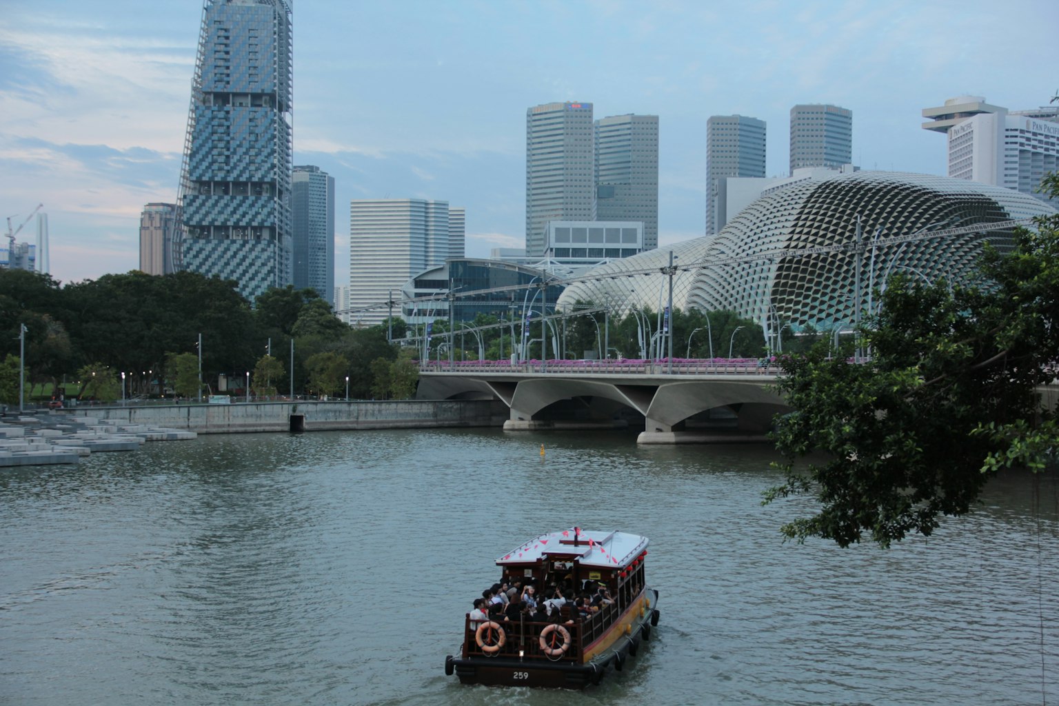 Barca turistica che naviga nel fiume a Singapore con edifici moderni