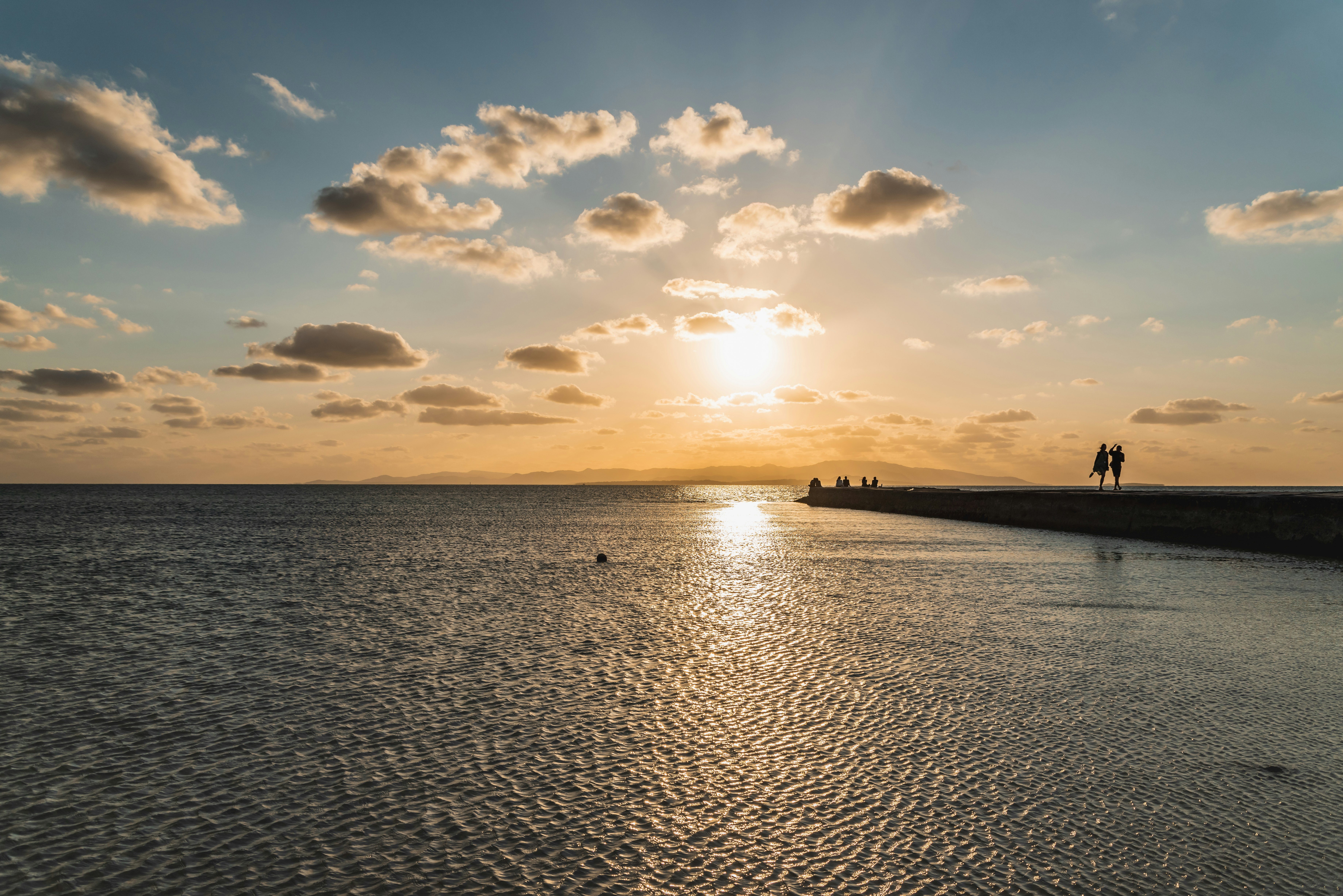 Tramonto sul mare con una diga e persone che passeggiano (Taketomi Island, Okinawa)