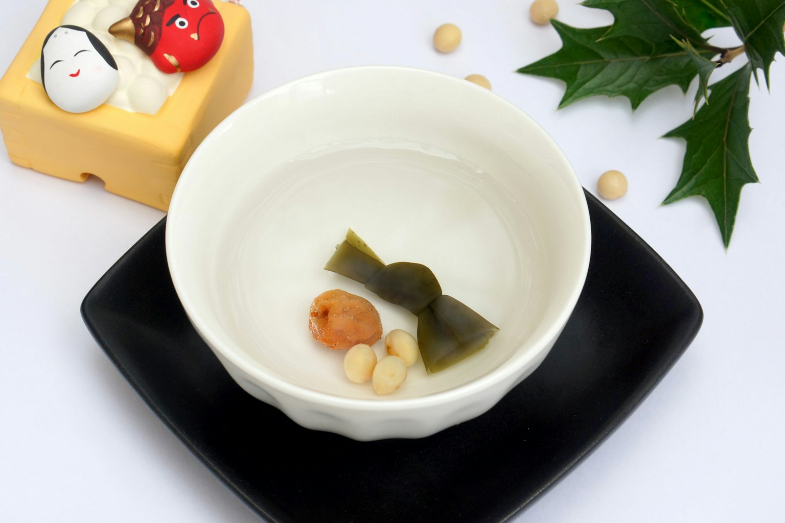 一個白碗裡裝著湯，裡面有海帶、醃漬梅子、銀杏和豆子