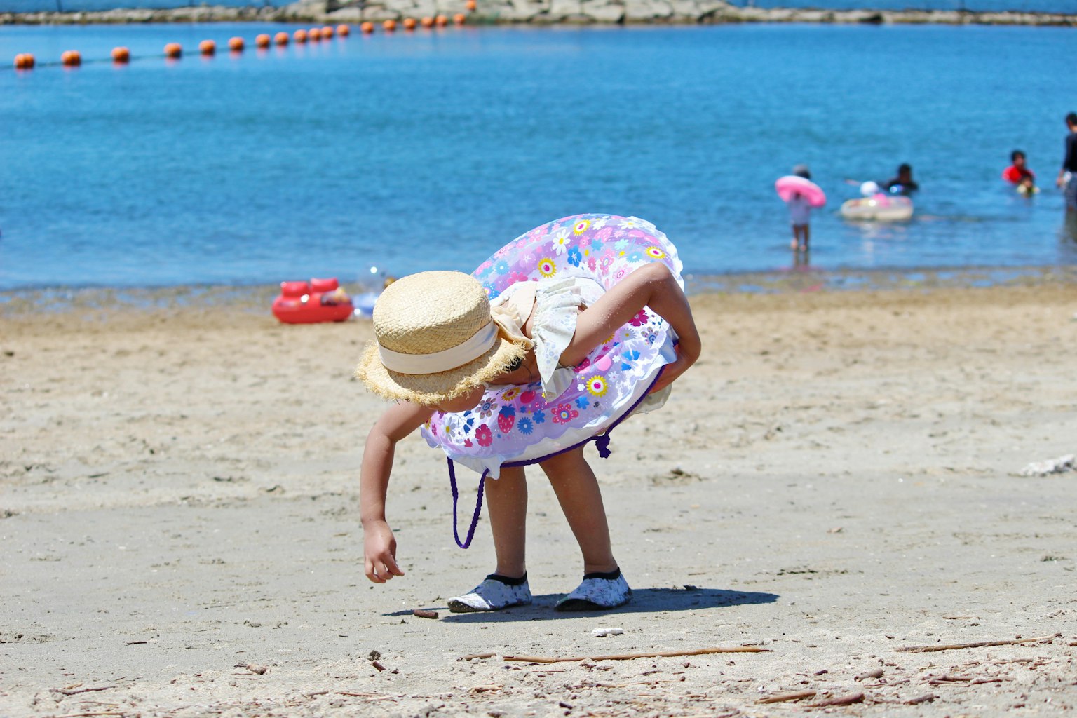 ビーチで砂を拾う子供の後ろ姿 青い海と人々がいる背景