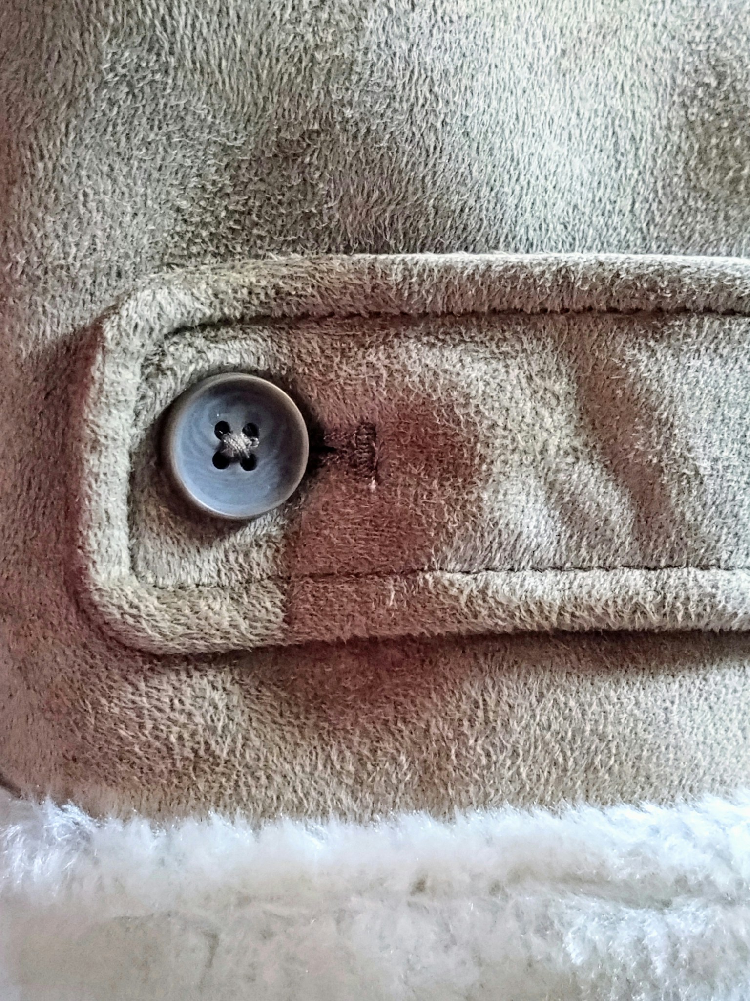 Close-up of a beige jacket button showcasing soft fabric and button details