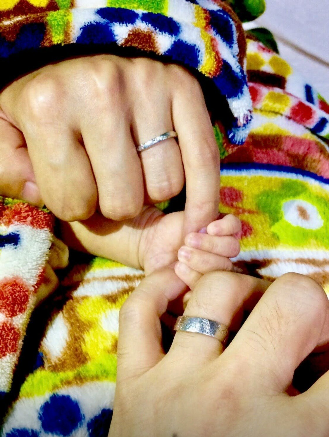 Family hands holding on a colorful blanket with rings