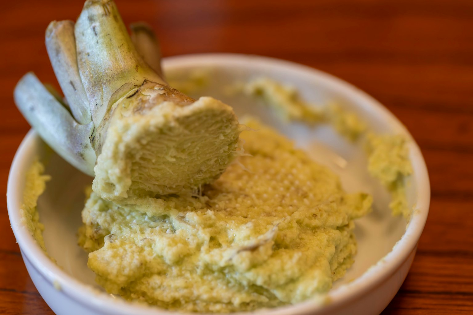 Radice di wasabi accanto a wasabi grattugiato fresco in una piccola ciotola