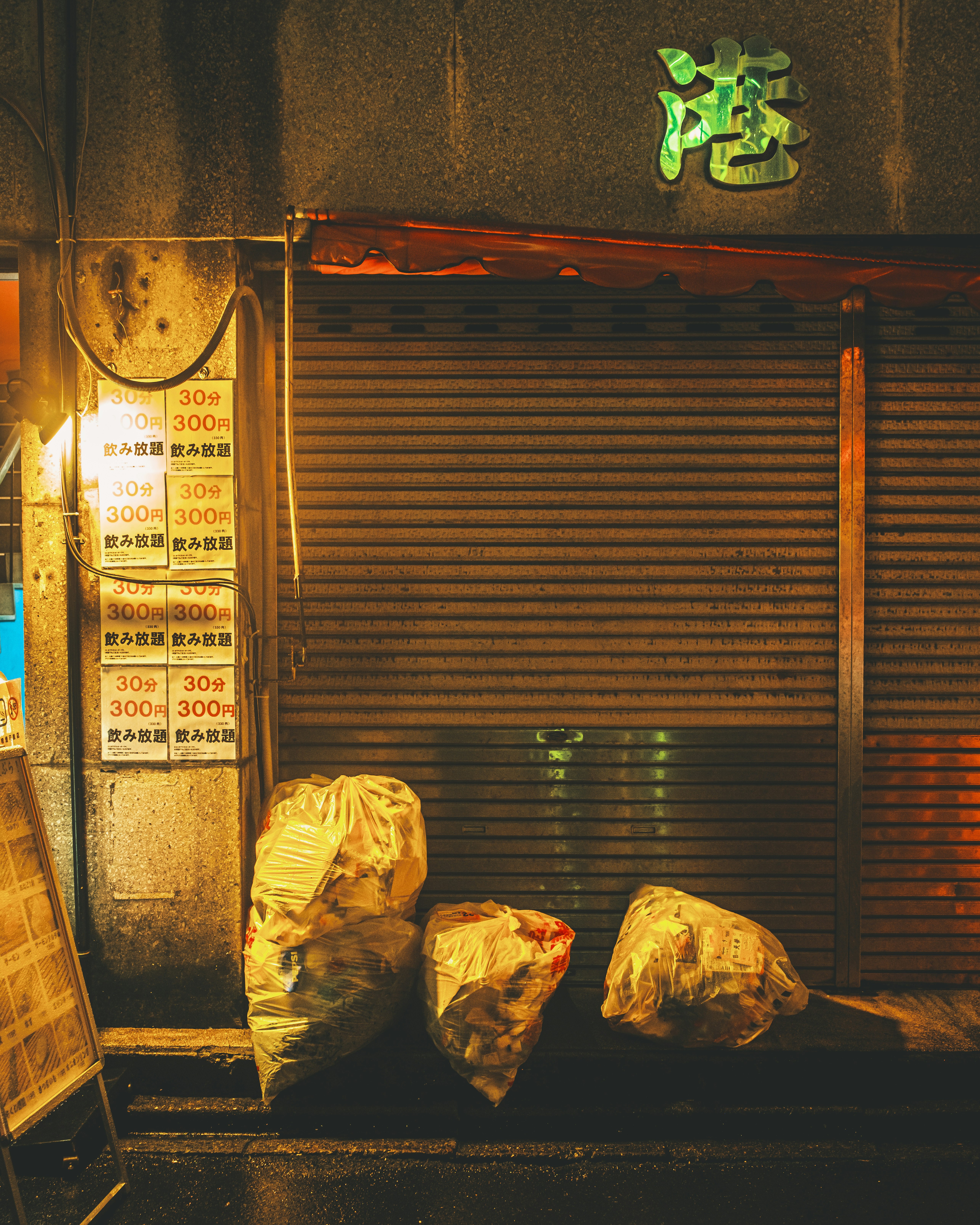 Boutique dans une ruelle sombre avec un panneau vert et de grands sacs poubelles devant