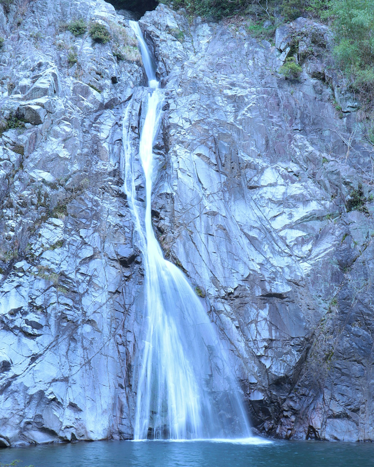 Air terjun biru mengalir di tebing berbatu