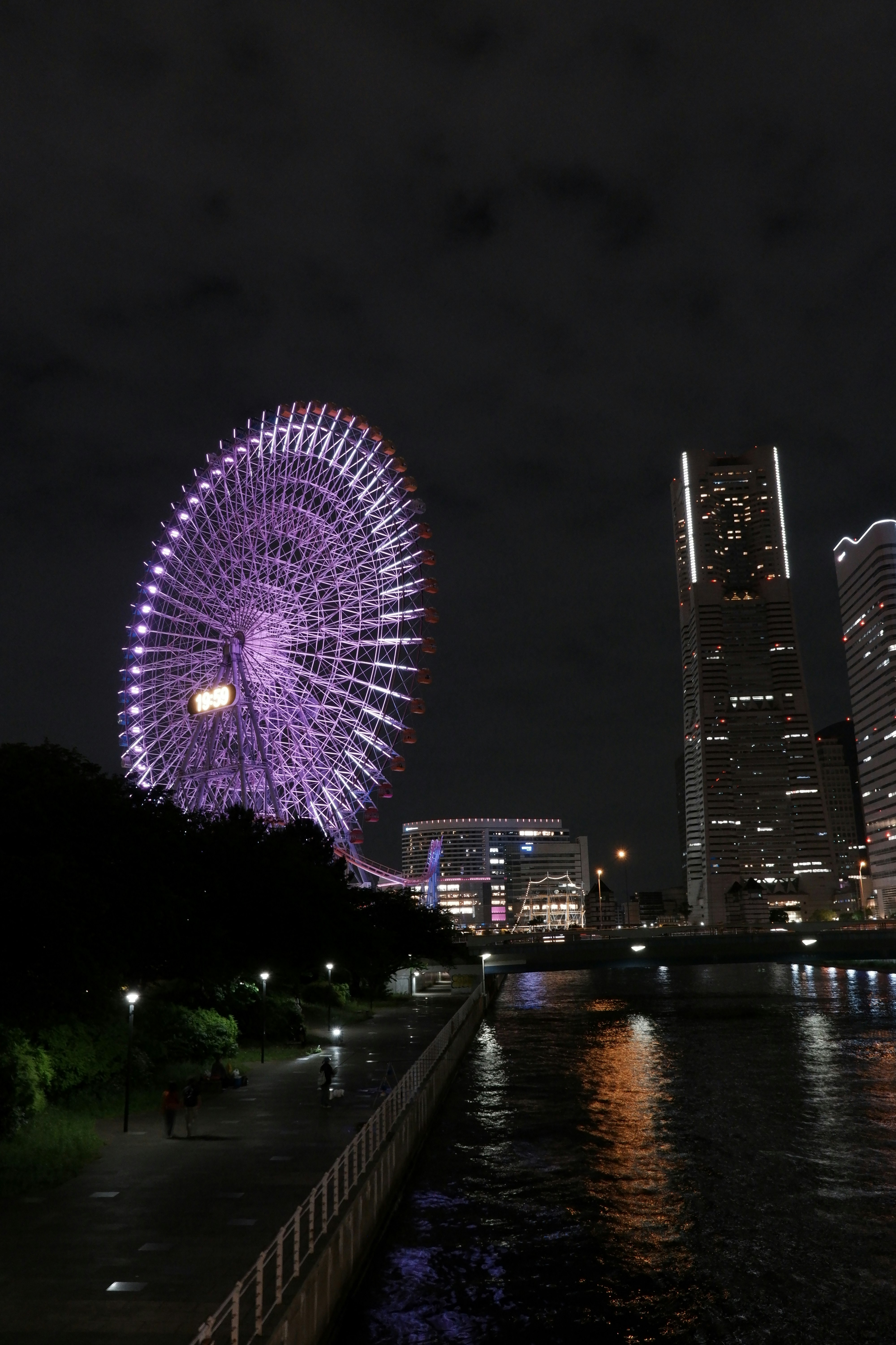 夜の川沿いと観覧車、ビル群の夜景