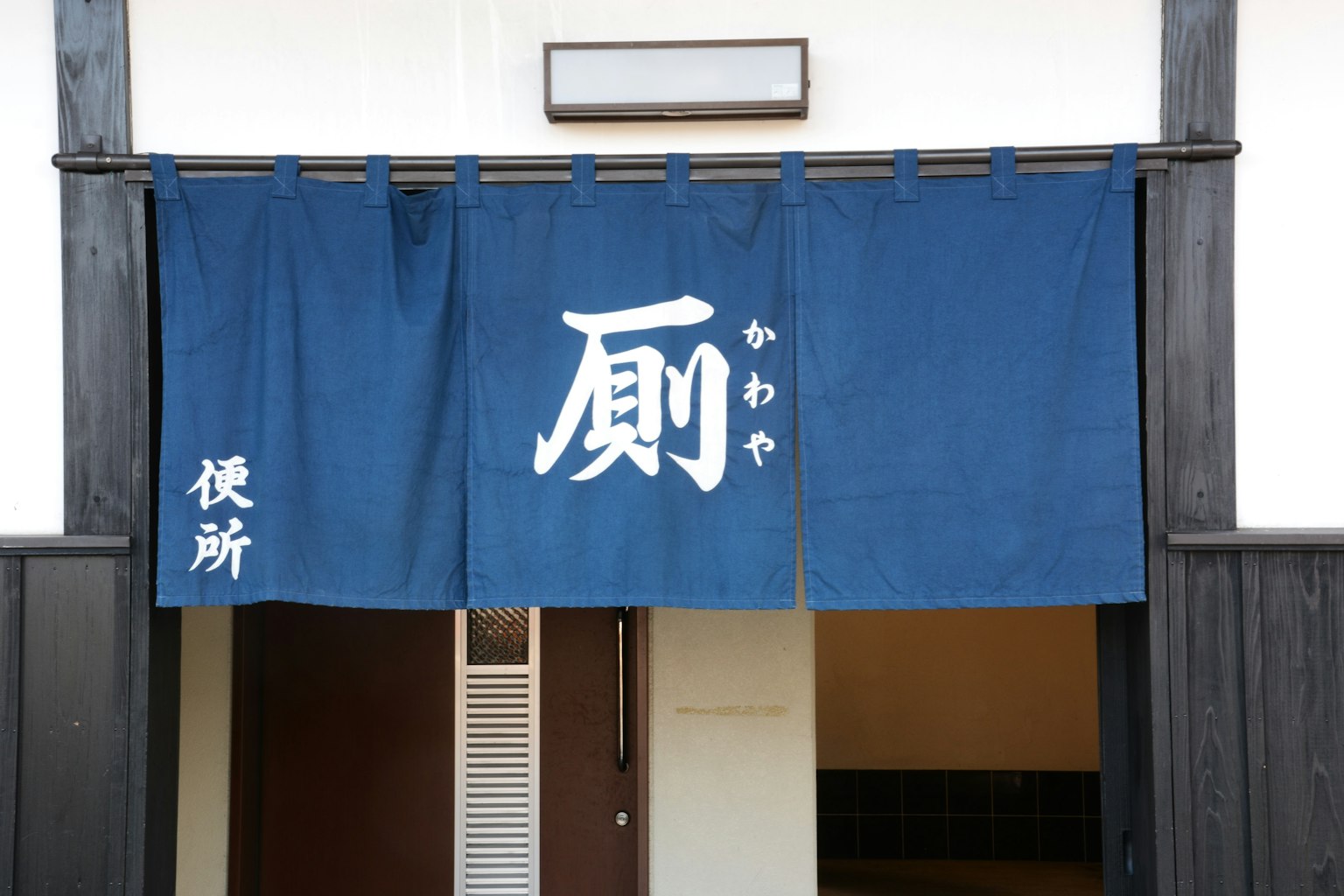 Traditioneller japanischer Eingang mit blauem Noren und dem Wort '扇'