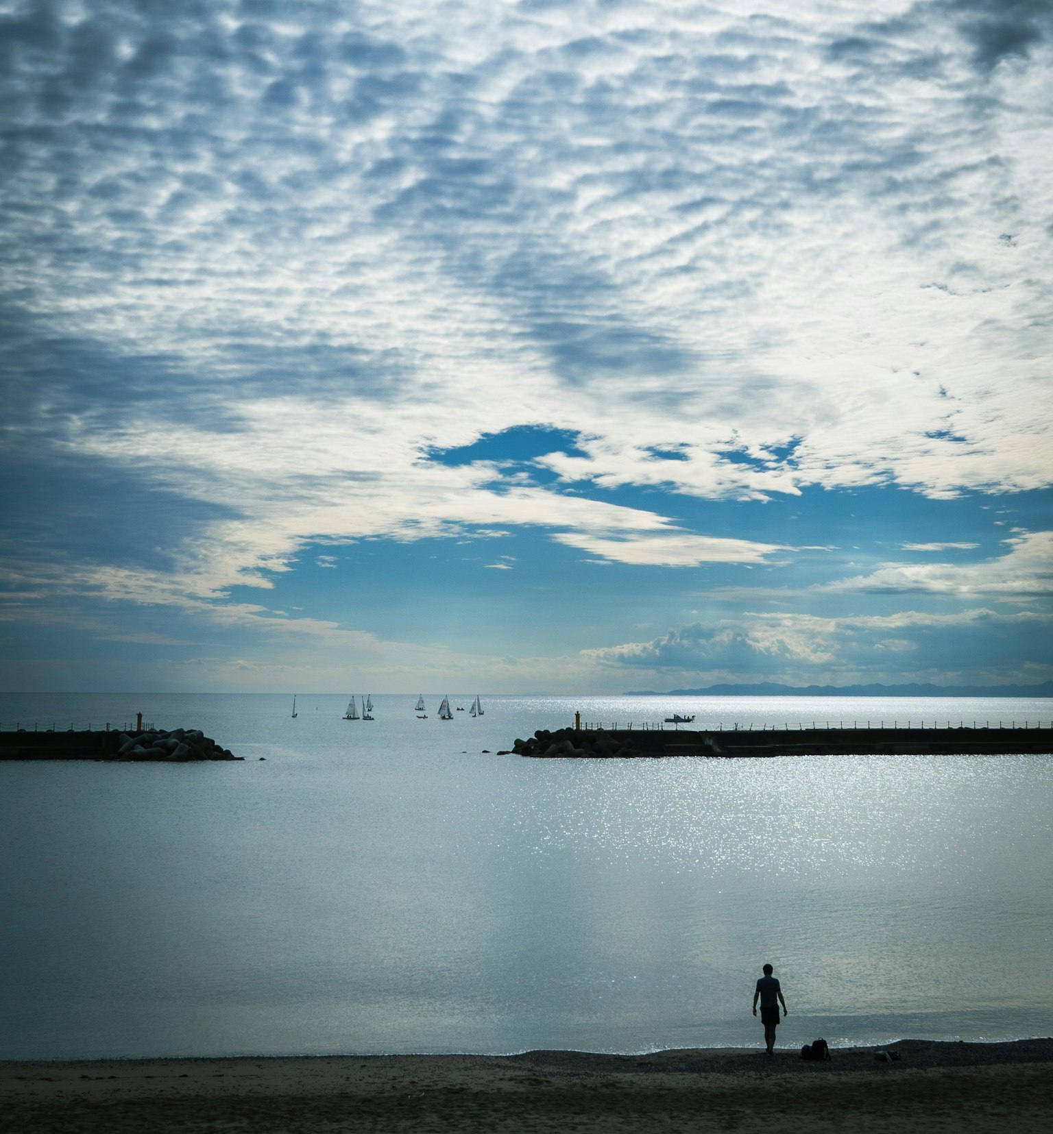 一个人站在海滩上，水面平静