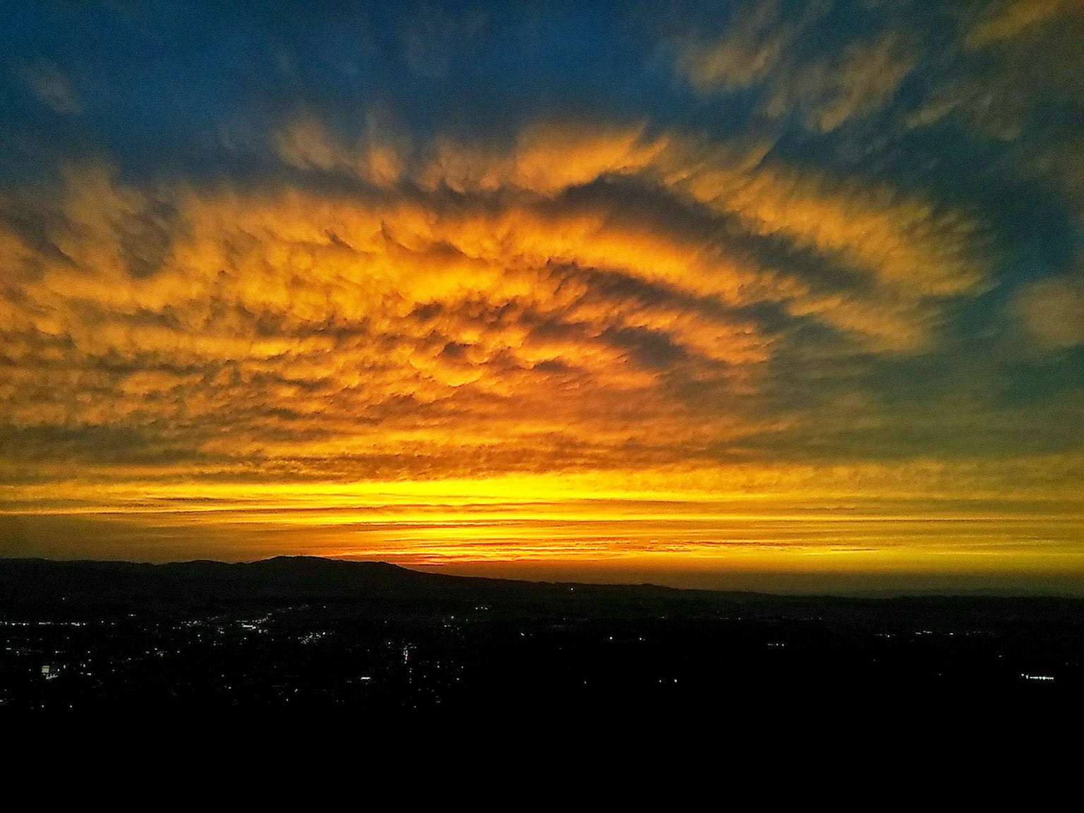 ท้องฟ้าสีสันสดใสในช่วงพระอาทิตย์ตกพร้อมเมฆหมุนและขอบฟ้า