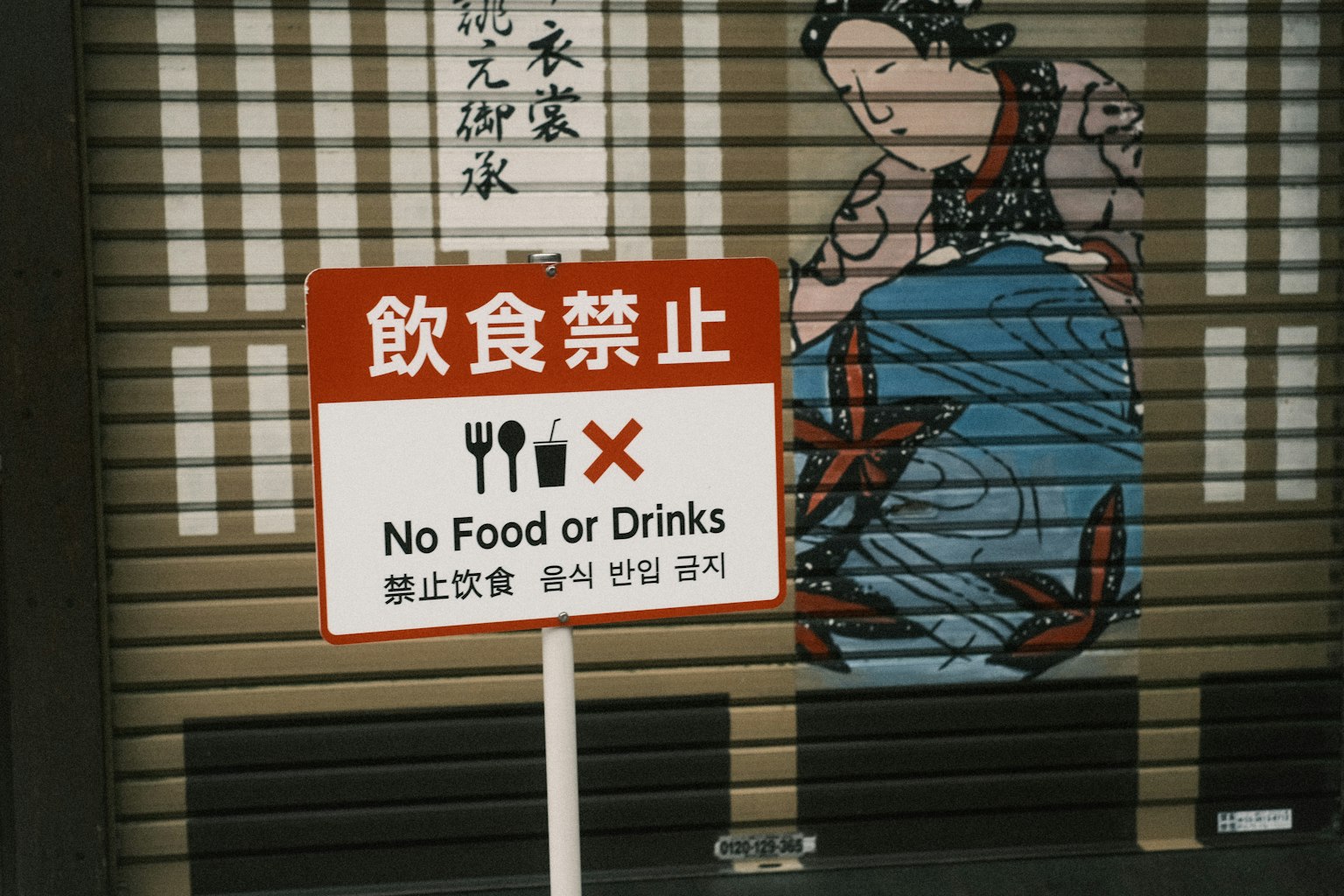 Papan merah yang menunjukkan larangan makanan dan minuman dengan ilustrasi Jepang tradisional