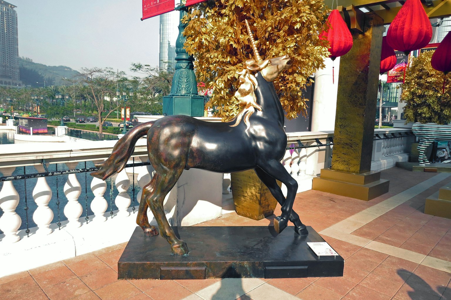A bronze statue of a unicorn with a child riding on it in an outdoor setting