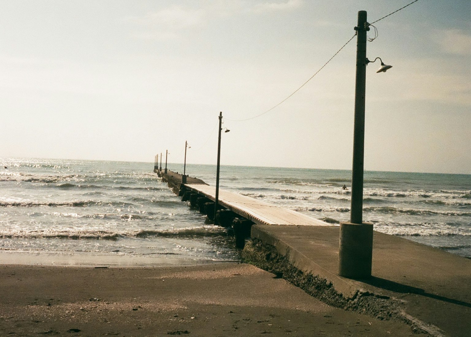 A view of a pier extending into the wavy sea