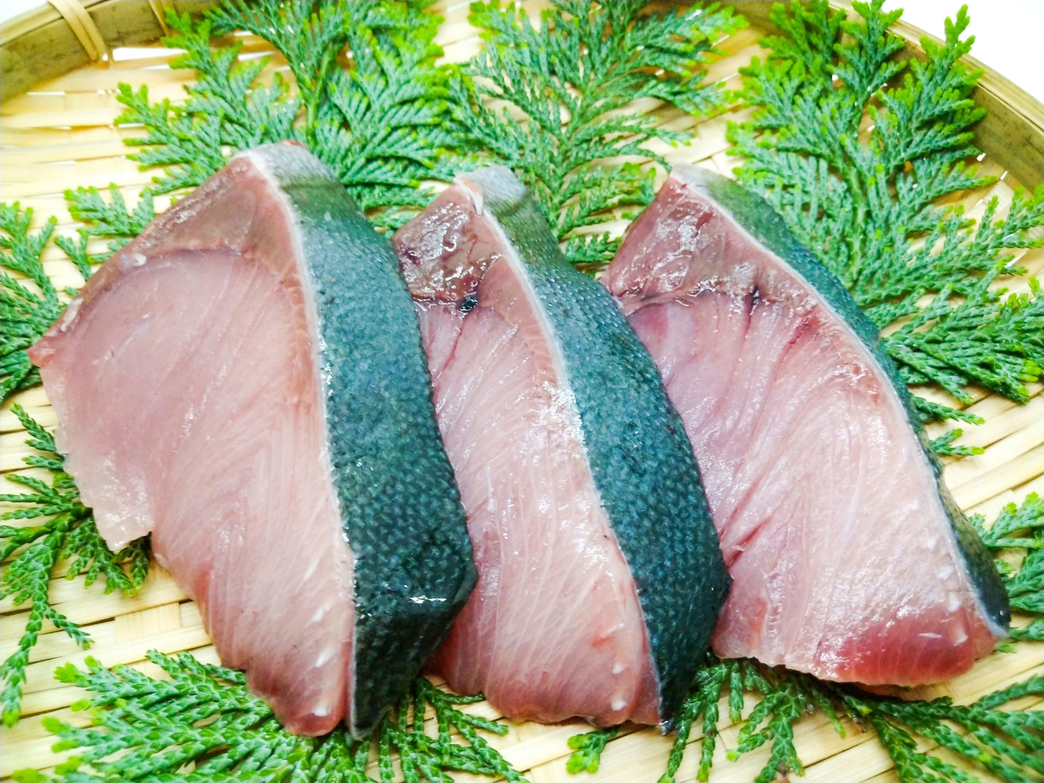 砧板上擺放的新鮮金槍魚排與綠色香草