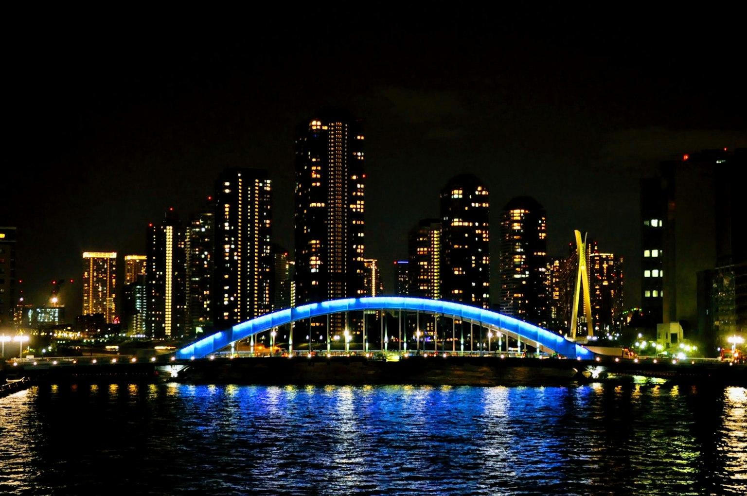 Skyline notturna della città con un ponte blu illuminato