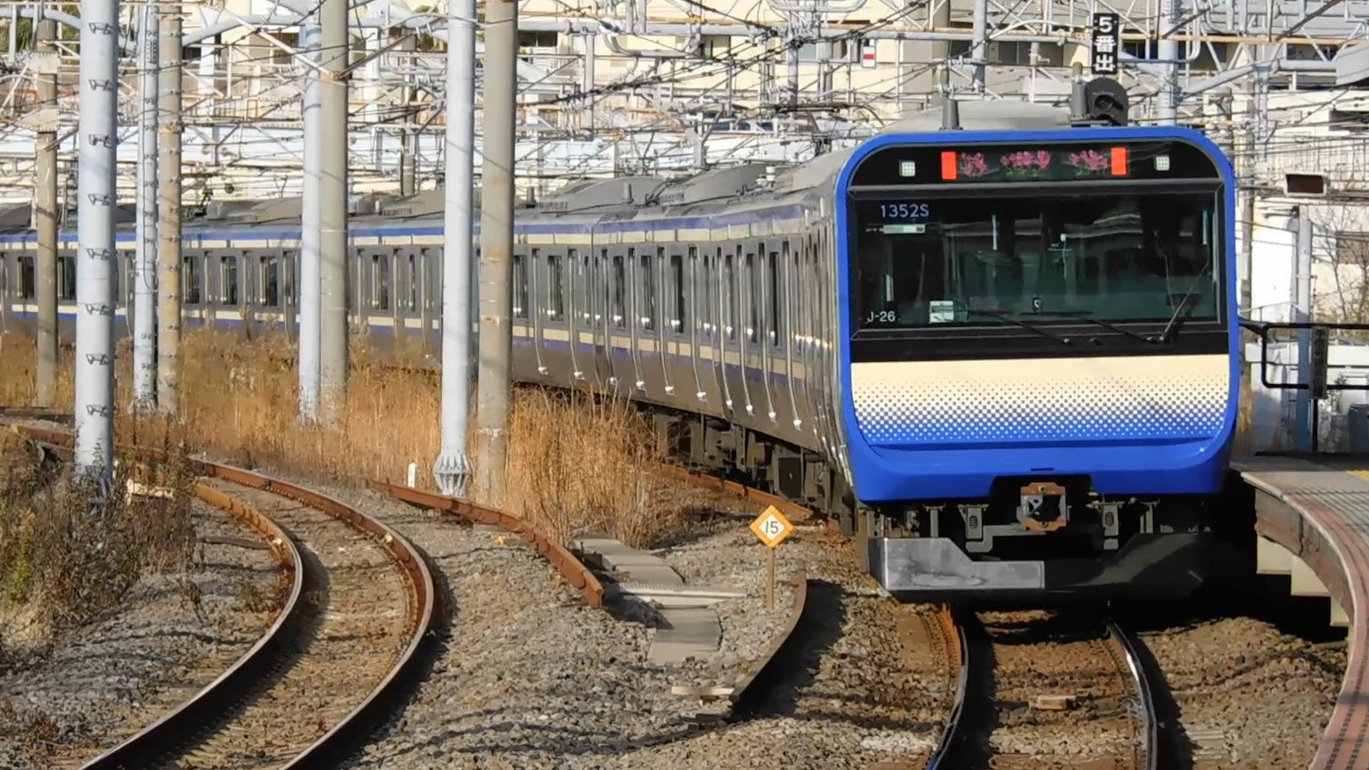 Un treno blu che naviga su binari curvi in un deposito ferroviario