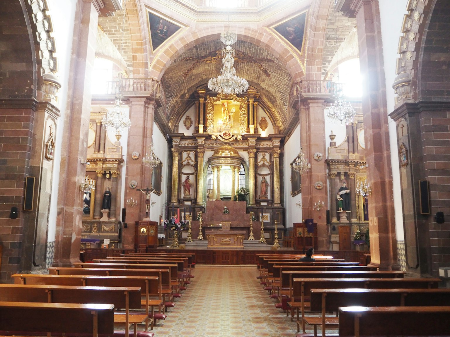 Innenraum einer Kirche mit kunstvollen Dekorationen und Reihen von Holzbänken