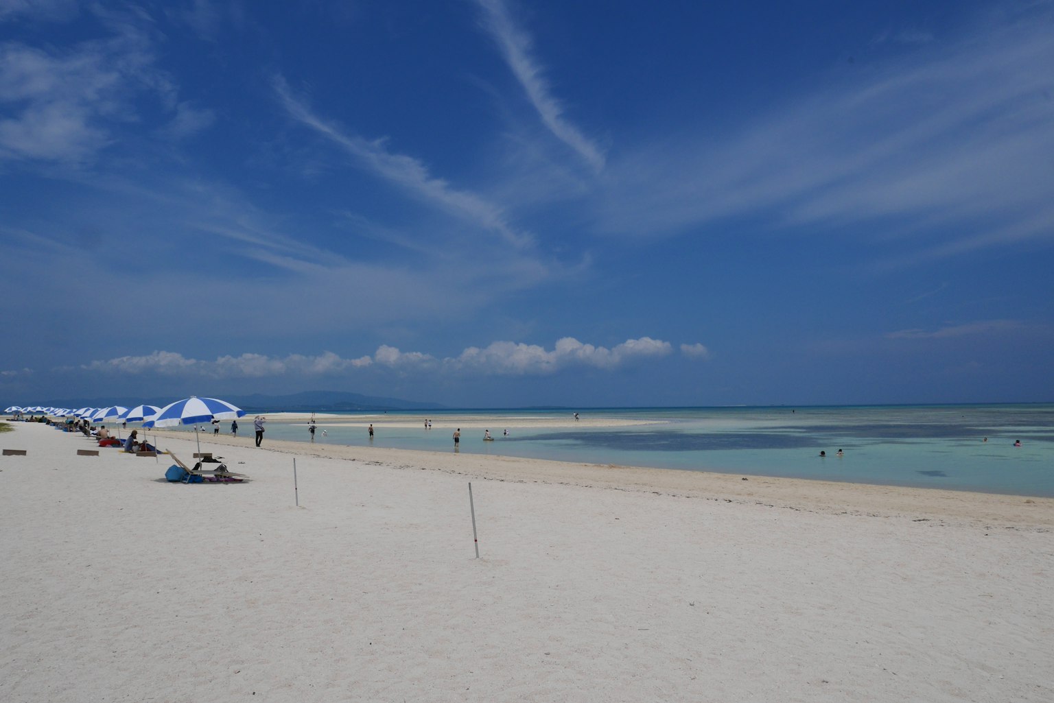 风景如画的海滩景观蓝天和白沙海滩旁边排列的遮阳伞