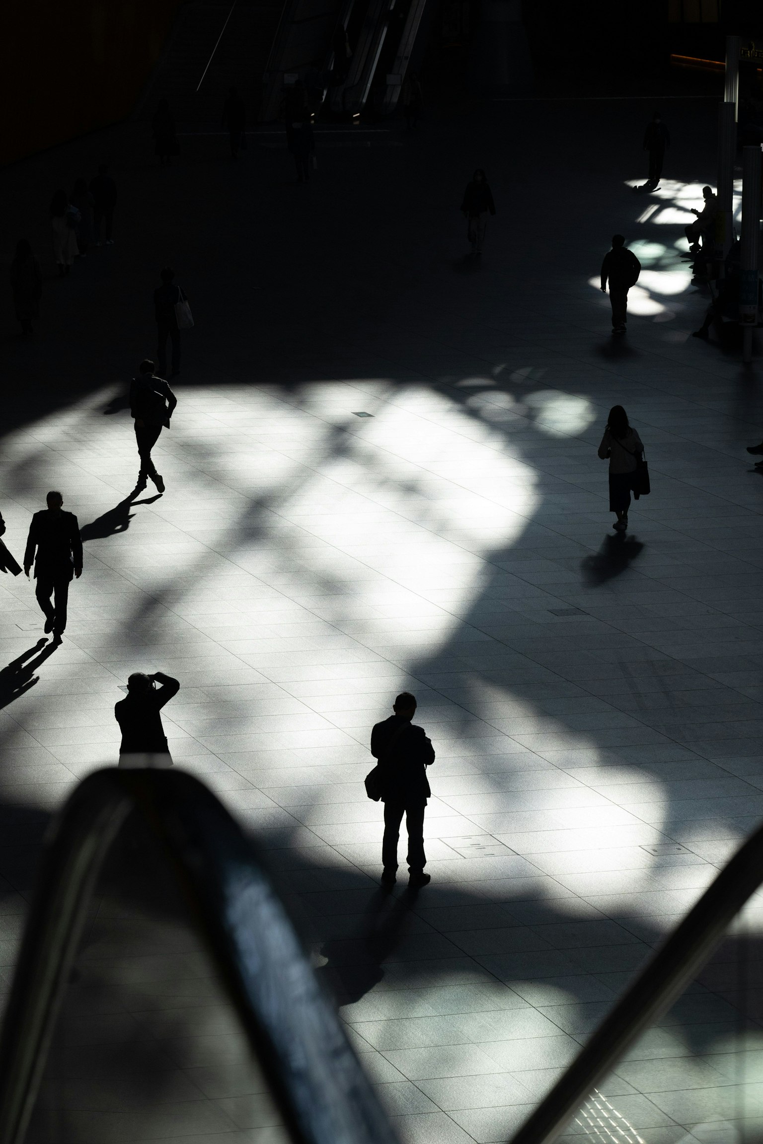 Personas caminando en sombras con patrones de luz en el suelo