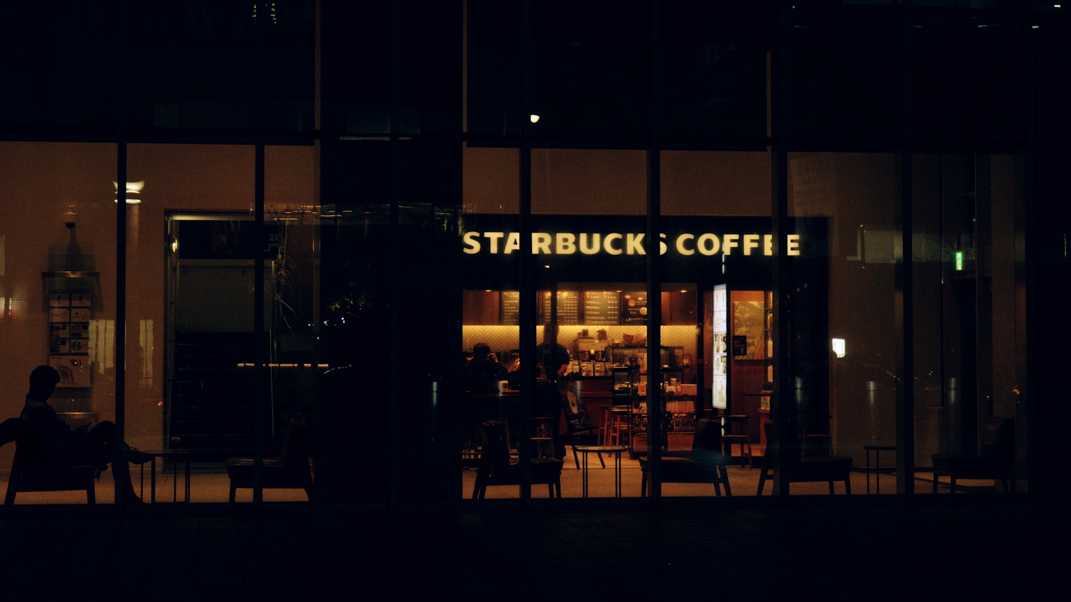 夜のスターバックスコーヒーの外観 光の中に人々が見える