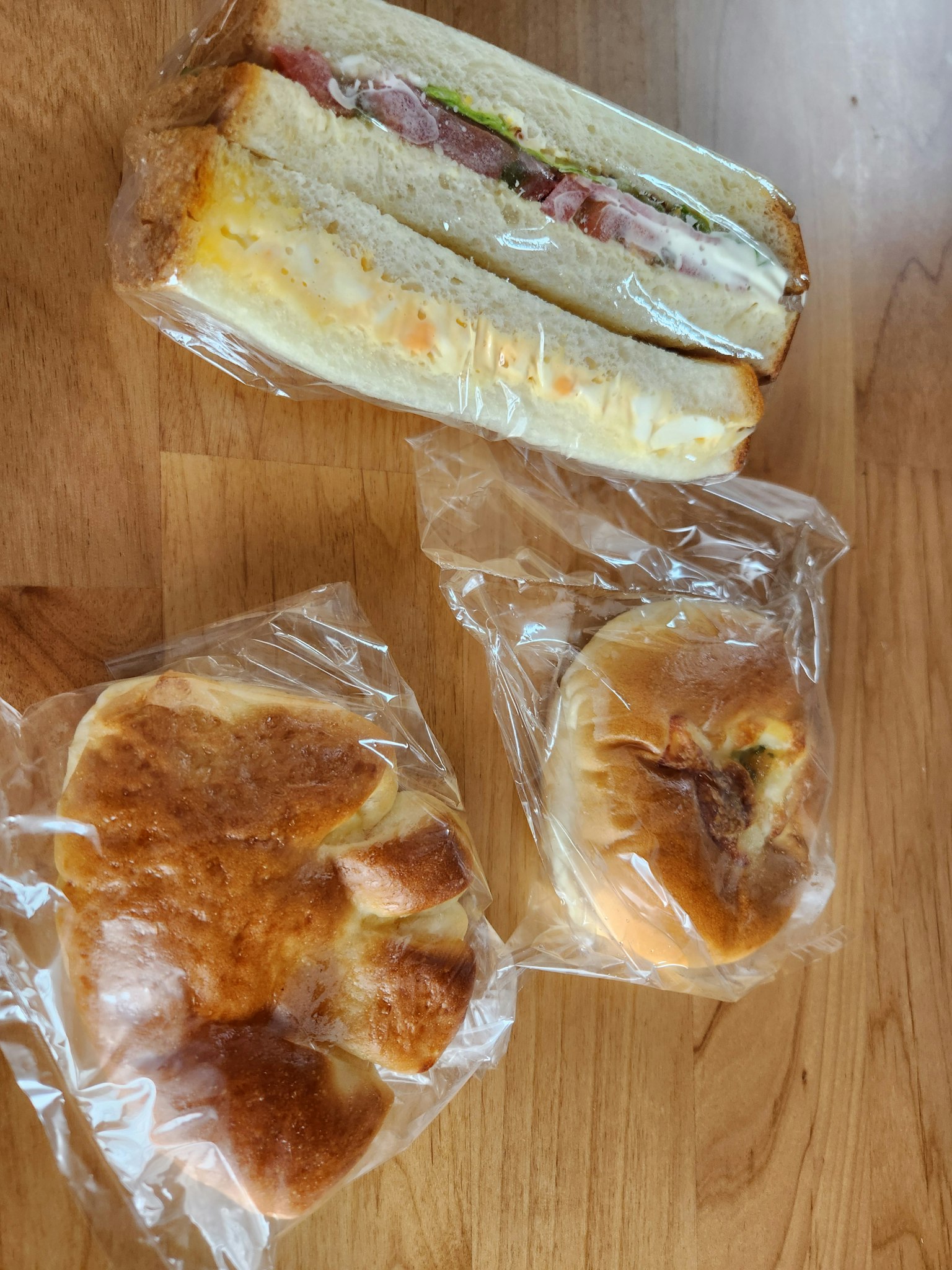 Hình ảnh của một chiếc bánh sandwich và hai loại bánh trên bàn gỗ
