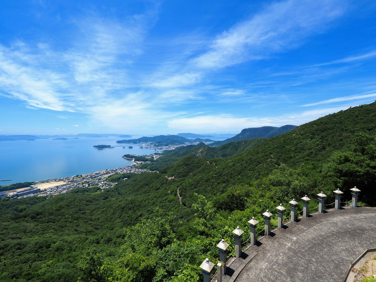 青山綠水的風景，背景是藍天和大海，前景有石燈籠