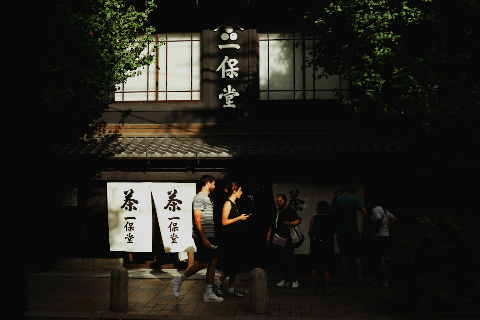 ภายนอกบ้านชาในถนนมืดที่มีผู้คนเดินผ่าน