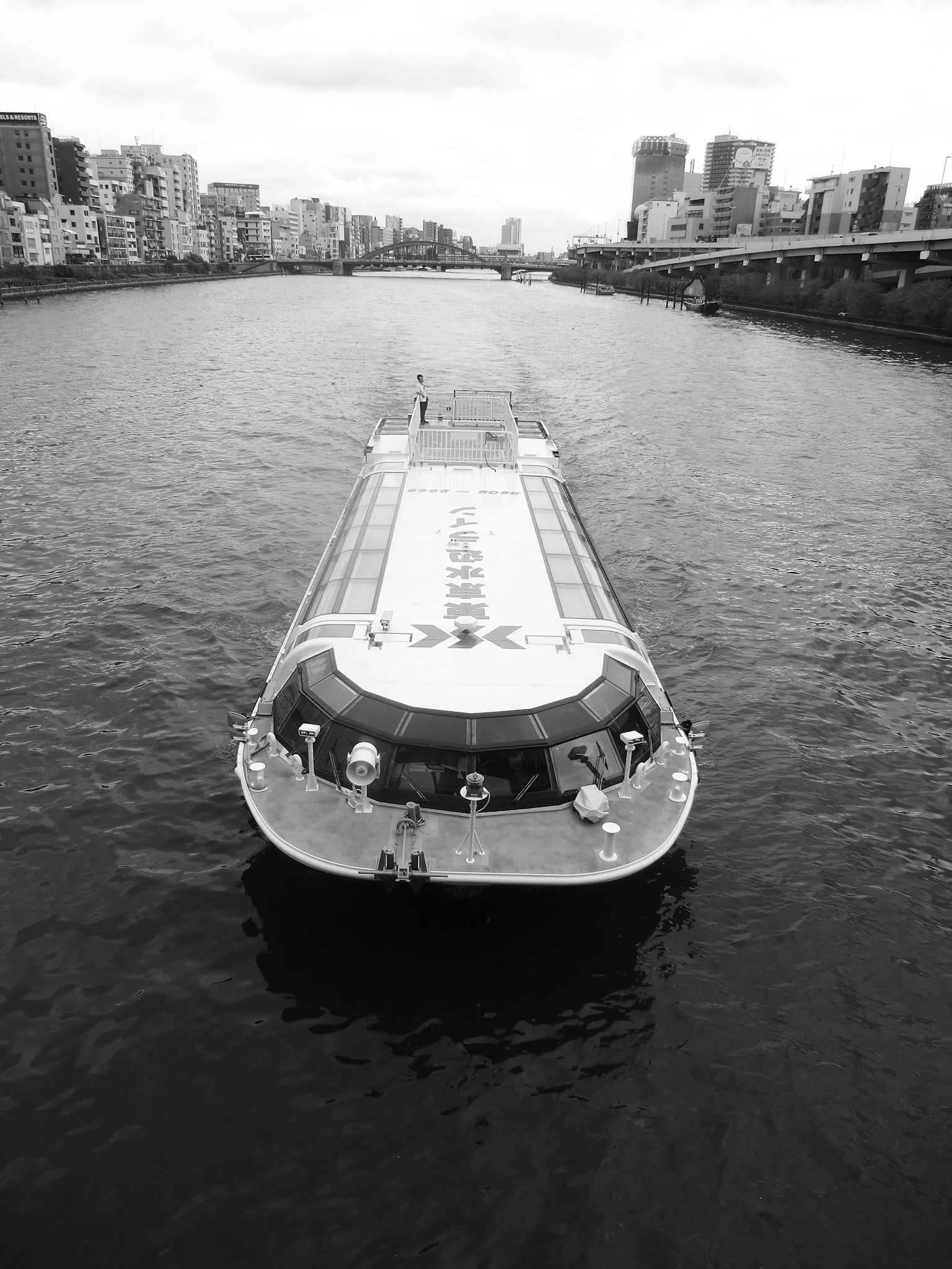 モノクロの川を進む船と都市の風景