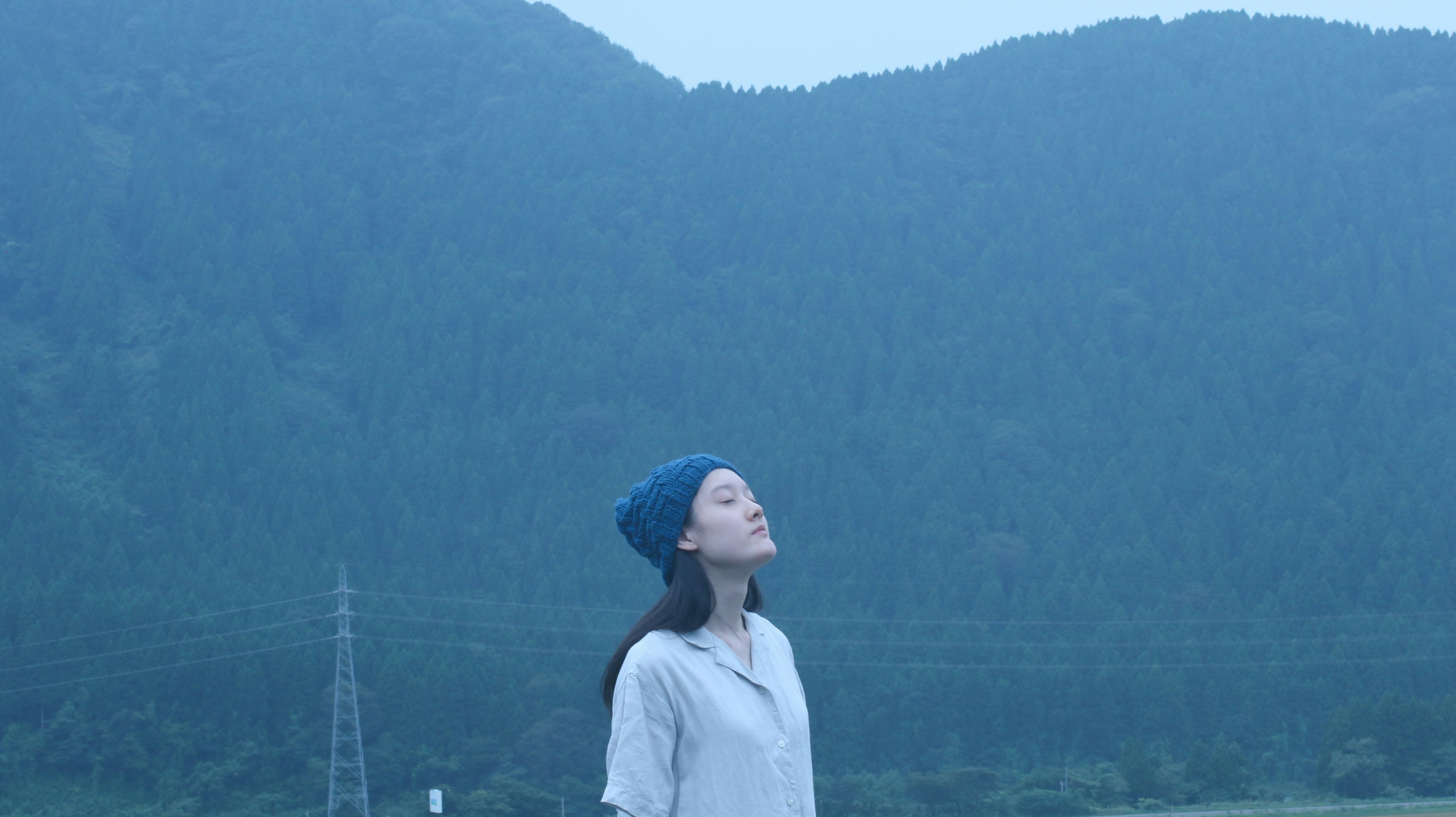 山あいの霧のような空気の中で佇む女性